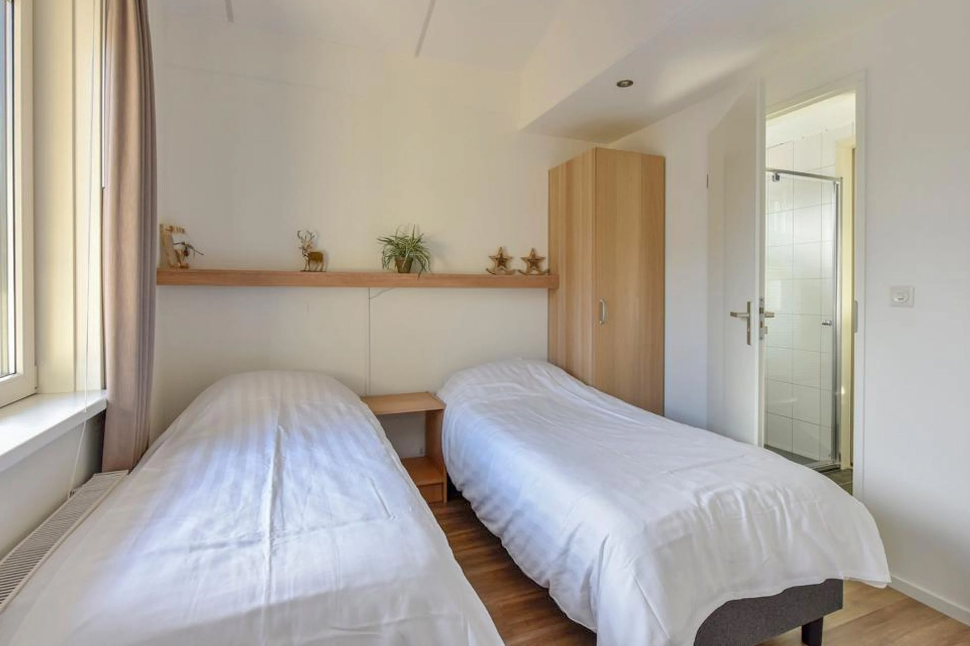Een slaapkamer met twee eenpersoonsbedden en een raam.