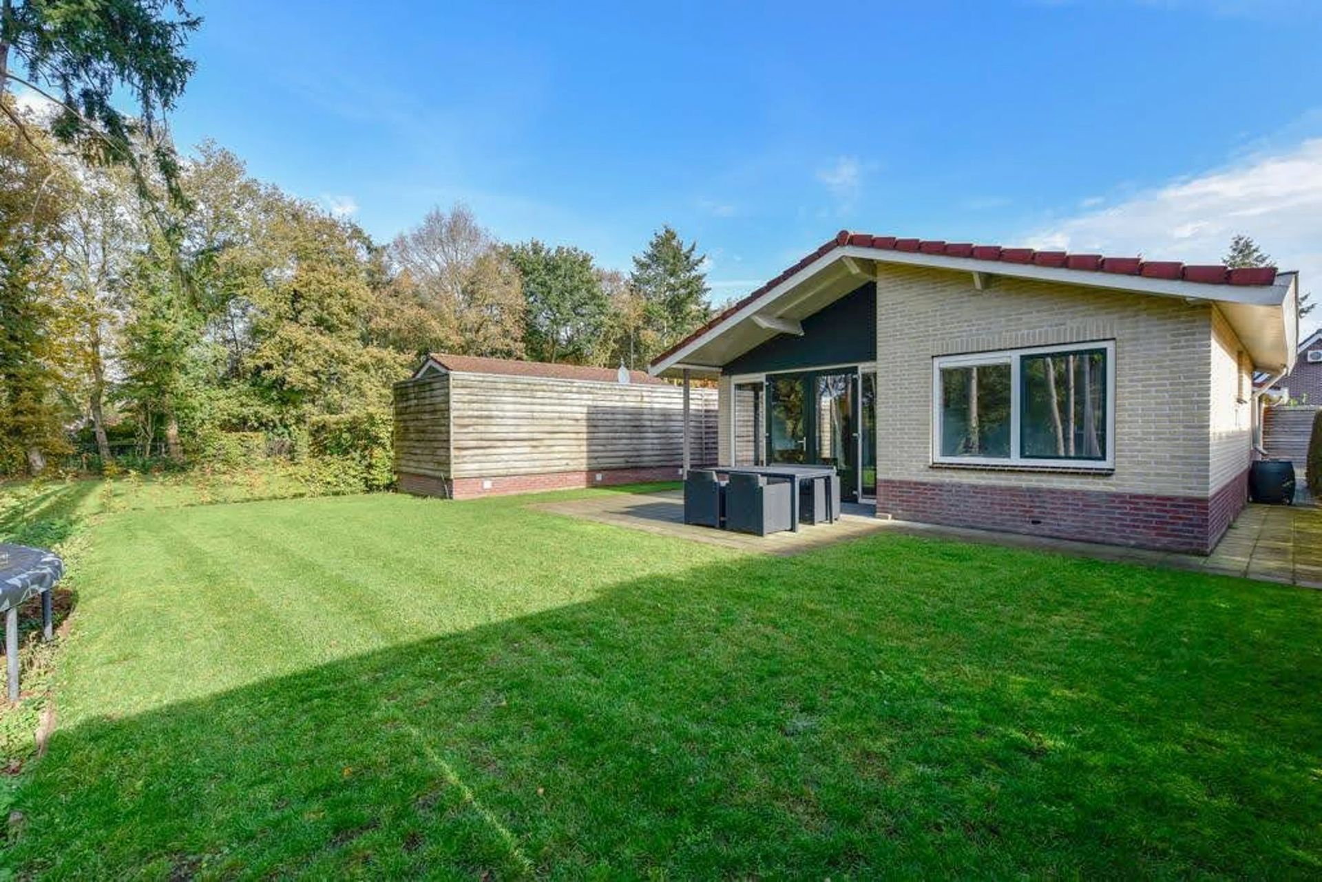 Een klein huis met een groot gazon ervoor.