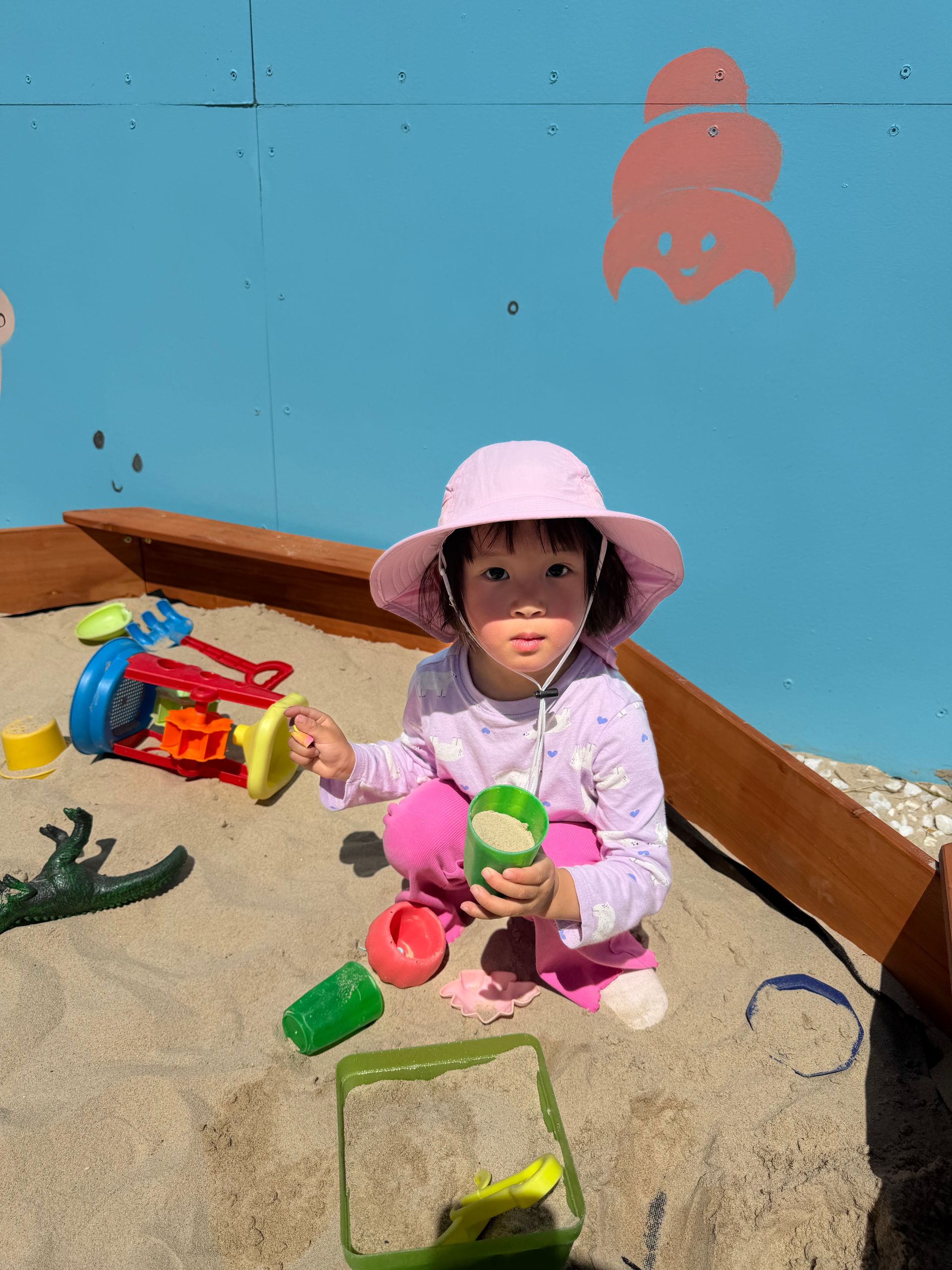 A little girl in a witch costume is standing next to a slide