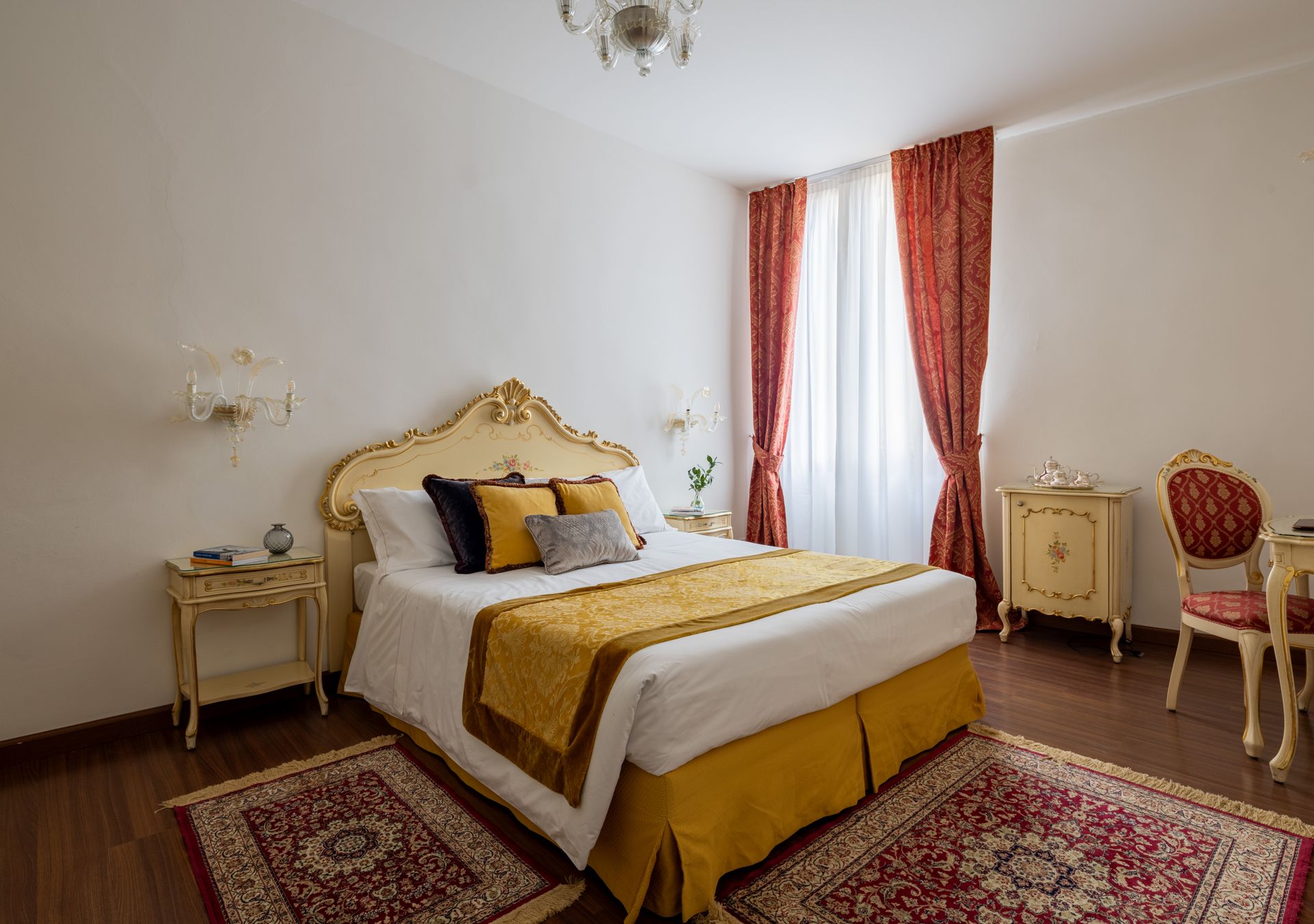 Elegante camera da letto con letto dorato riccamente decorato, tende rosse e tappeti a motivi geometrici.