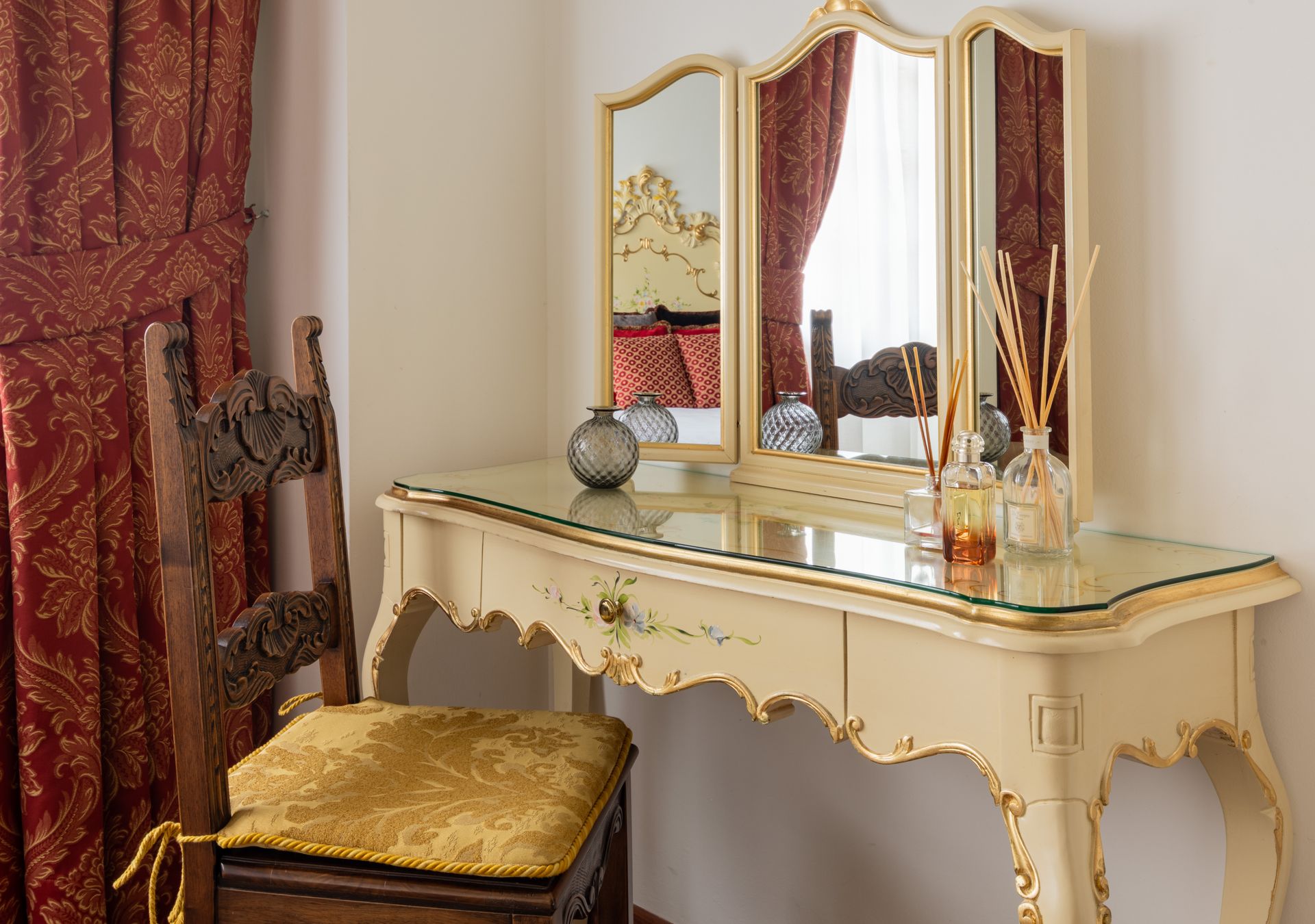 Elegante tavolo da trucco con specchio, sedia e tende rosse in una stanza classica