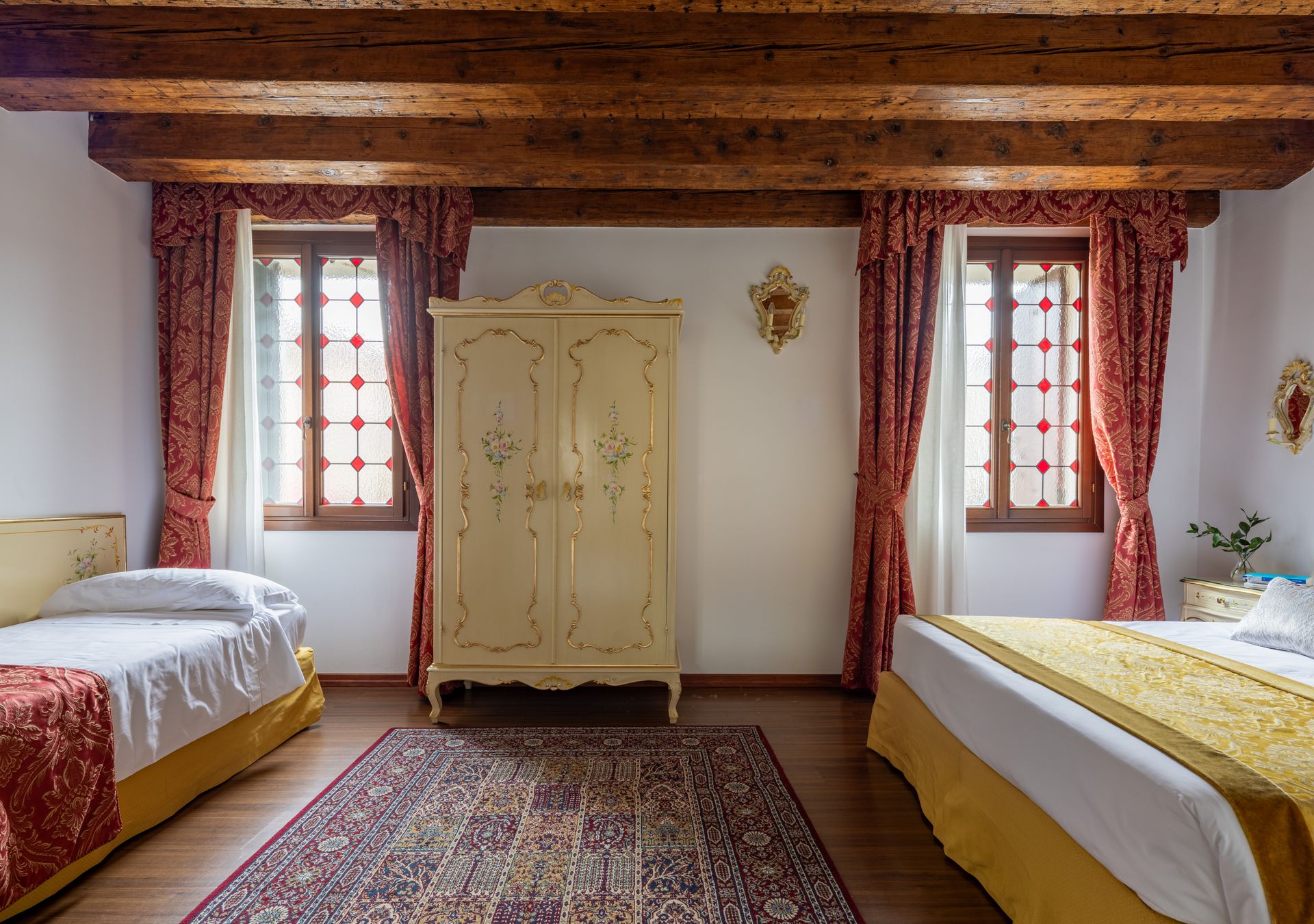 Accogliente camera da letto con due letti singoli, un armadio color crema, un tappeto a motivi geometrici