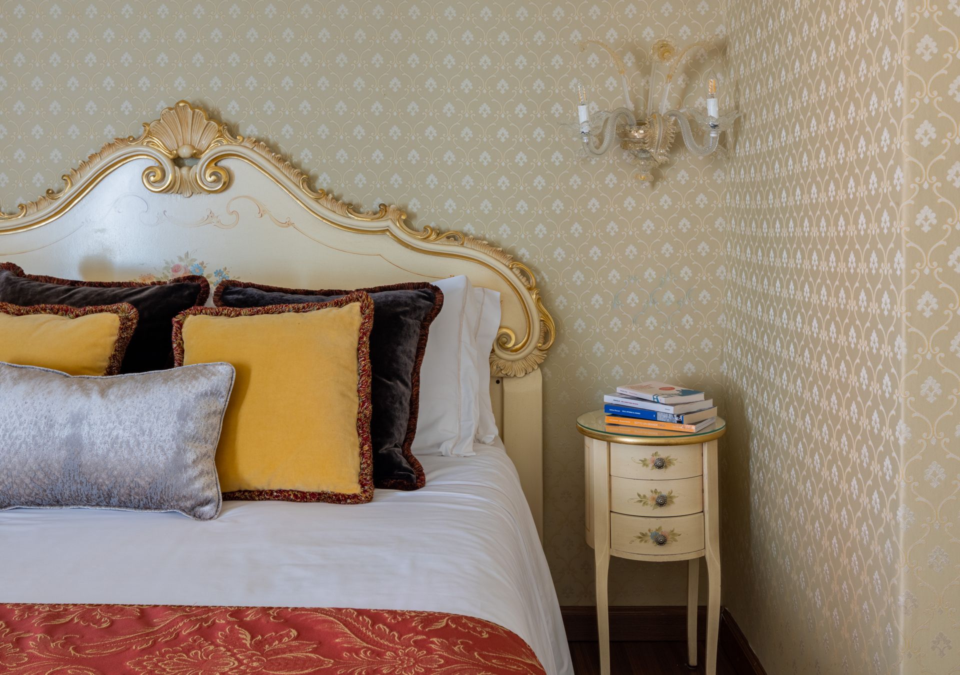 Elegante camera da letto con letto decorato bianco e oro, carta da parati a motivi geometrici