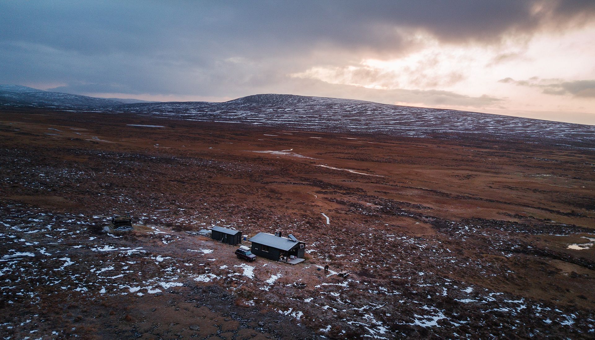 An aerial view of a snowy field with a mountain in the background.
