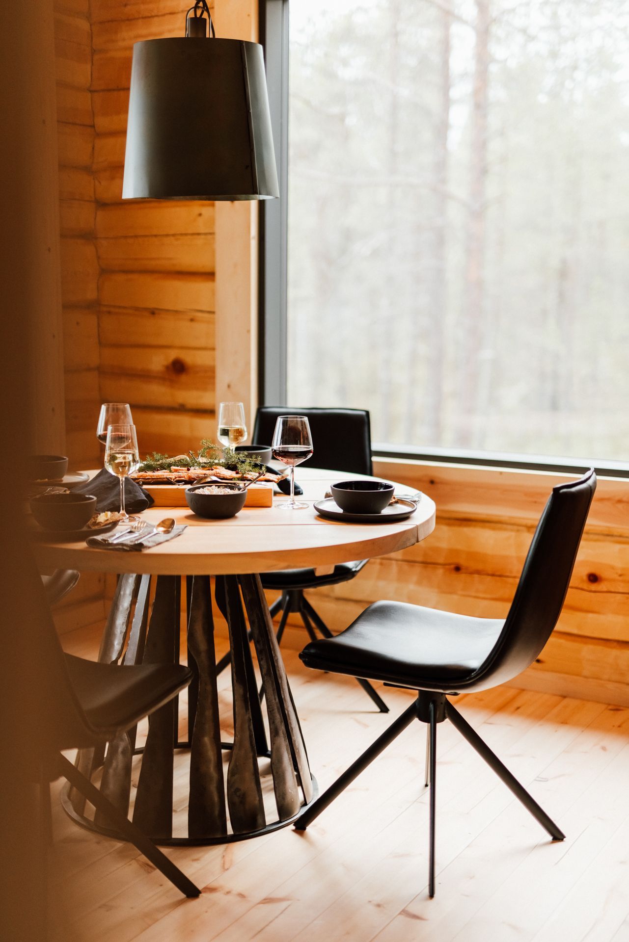 A wooden dining room with a table and chairs in front of a window.