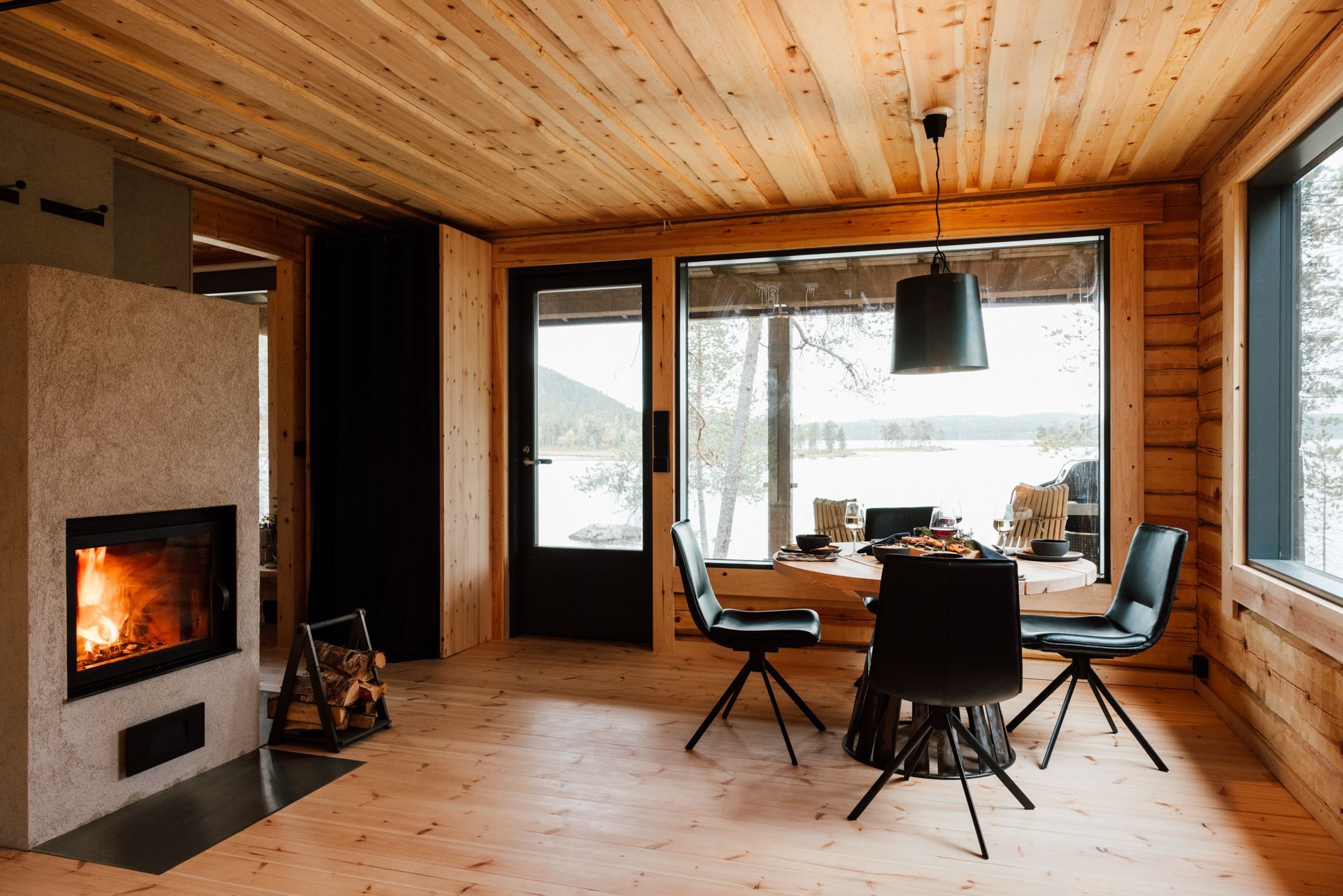 A dining room in a log cabin with a fireplace and a table and chairs.