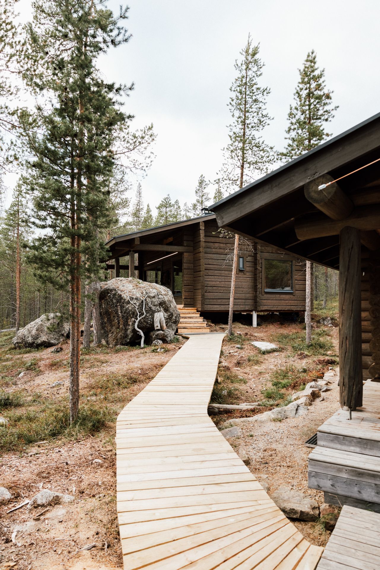 A wooden walkway leading to a log cabin in the woods.