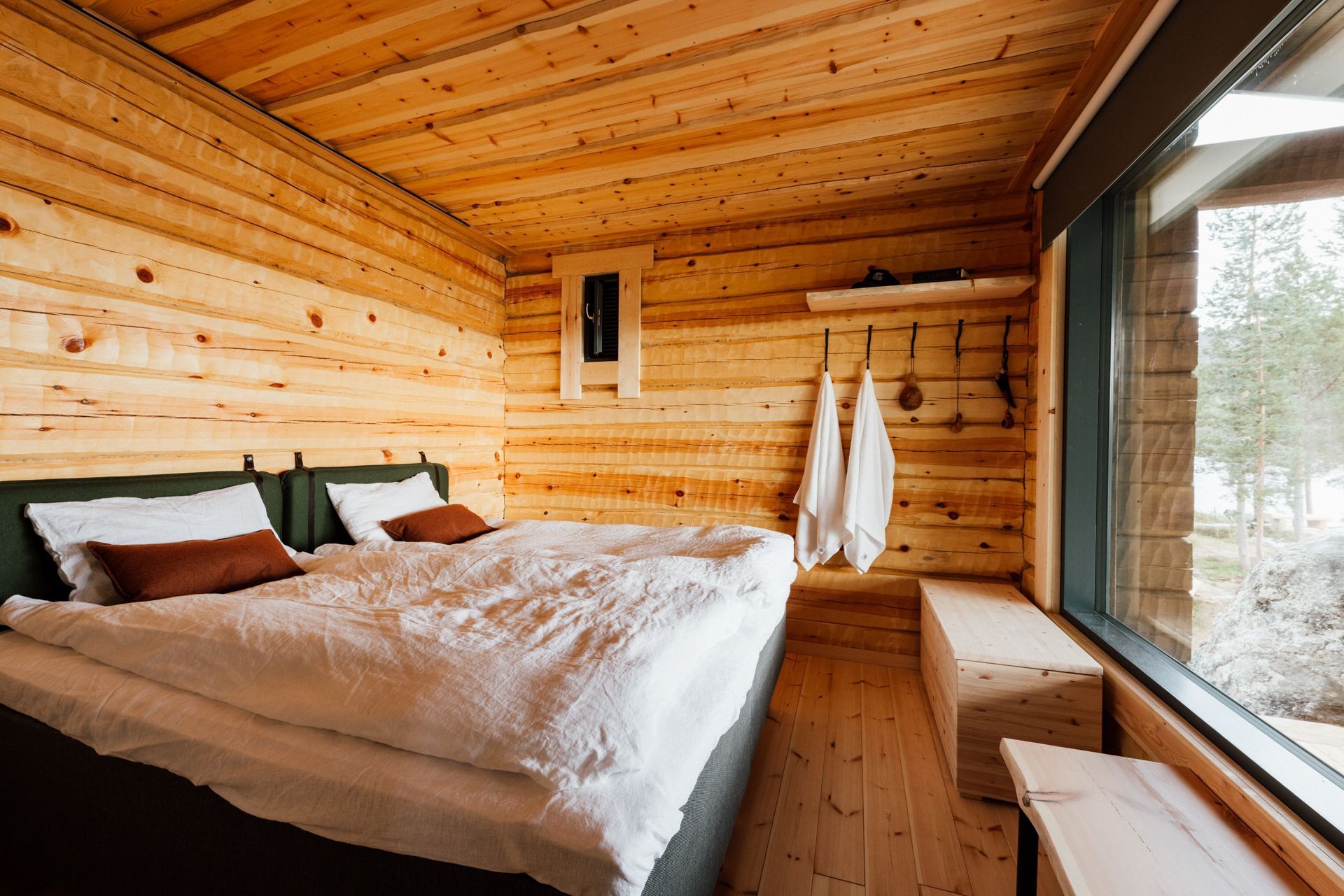 A bedroom in a log cabin with a large bed and a window.