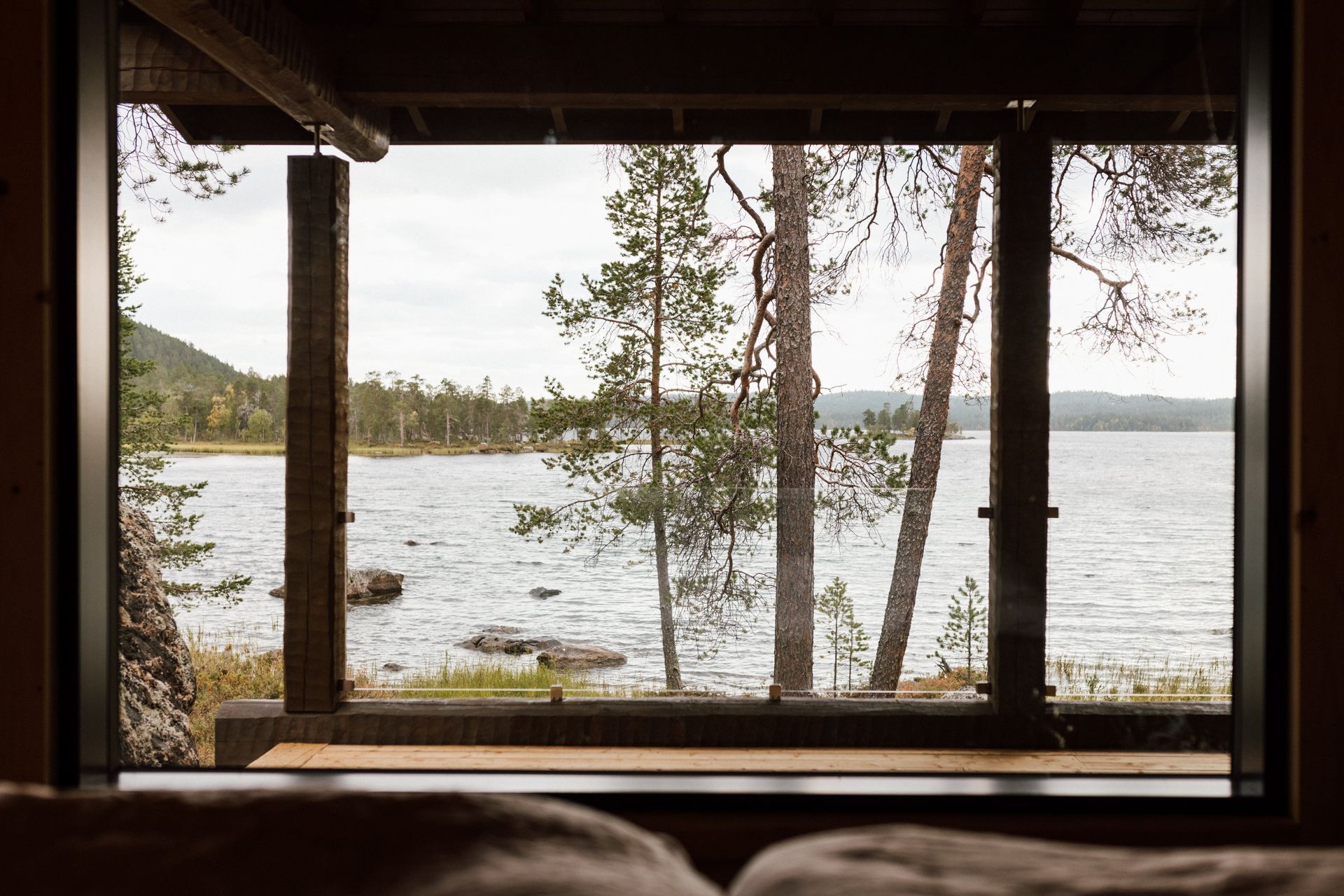 A view of a lake through a window with trees in the background.