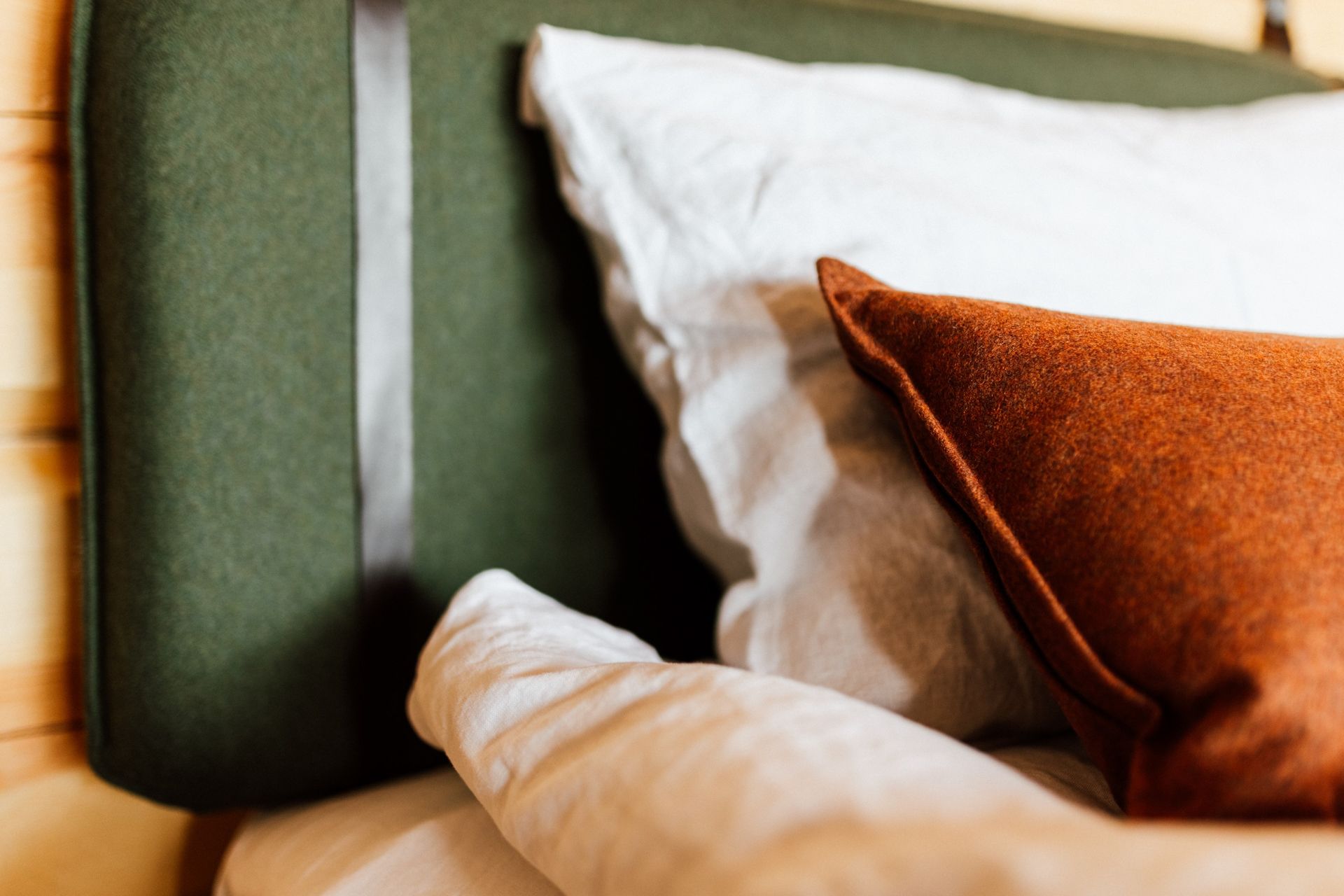 A bed with a green headboard and pillows on it.