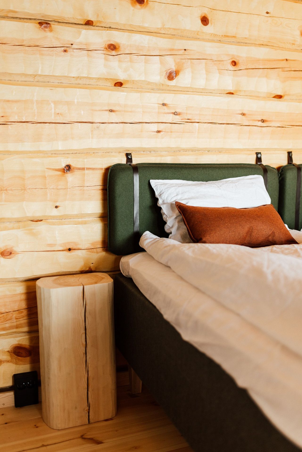 A bedroom with a bed , nightstand , and wooden wall.