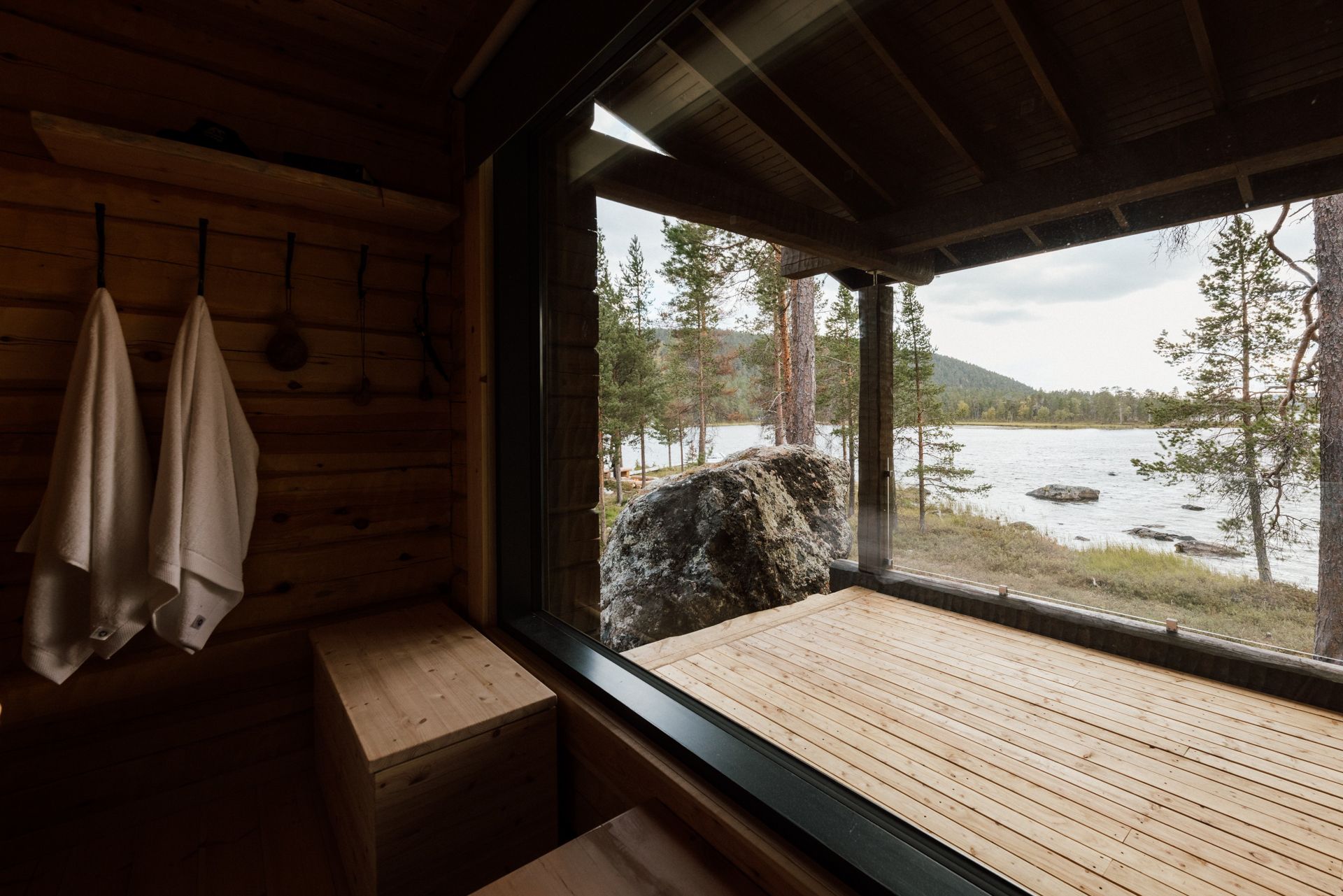 A wooden sauna with a view of a lake.
