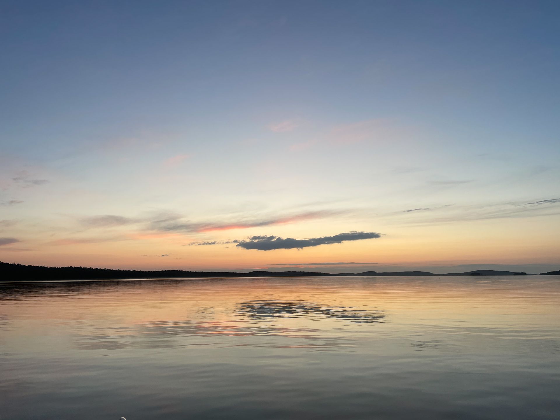 A sunset over a body of water with a cloud in the sky