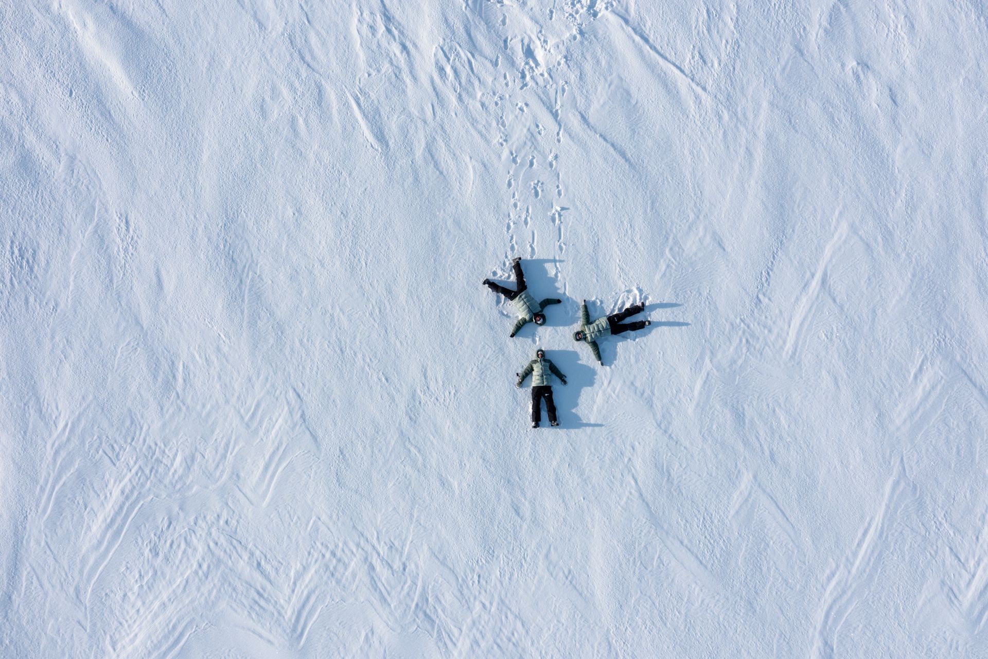 People making snow angels in a snowy field. Overhead shot.