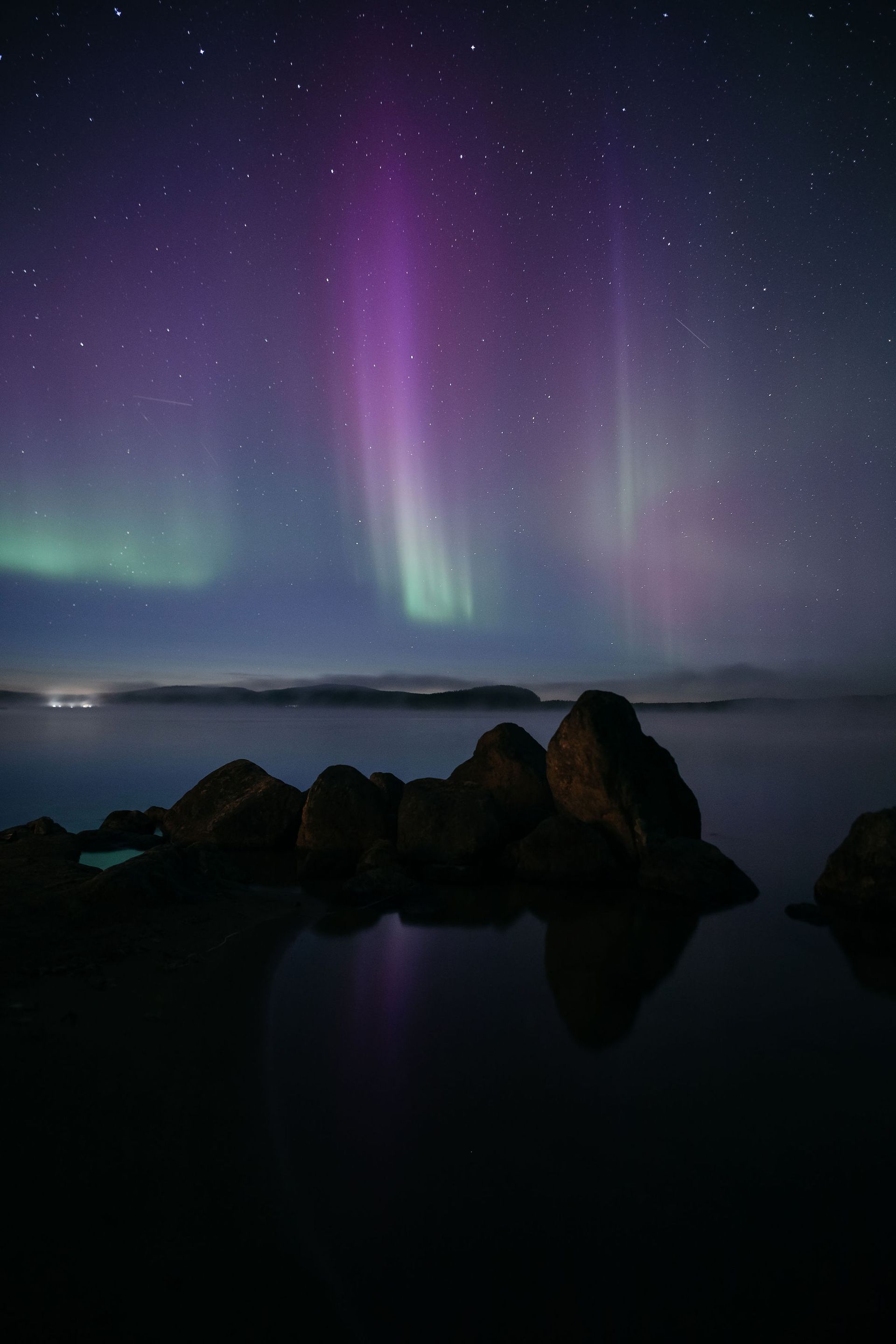 The aurora borealis is glowing in the night sky over a body of water.