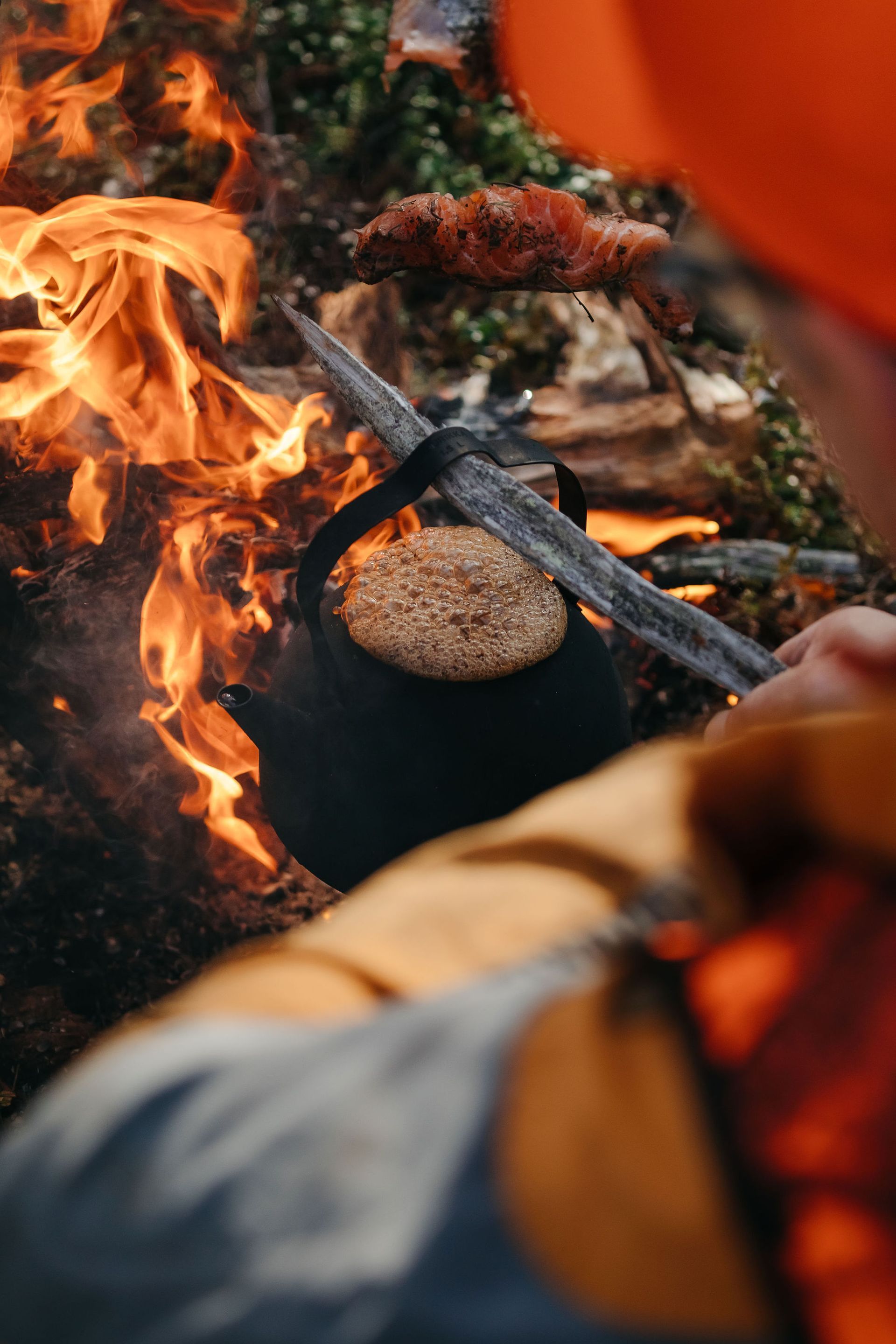 A person is making coffee over a campfire.