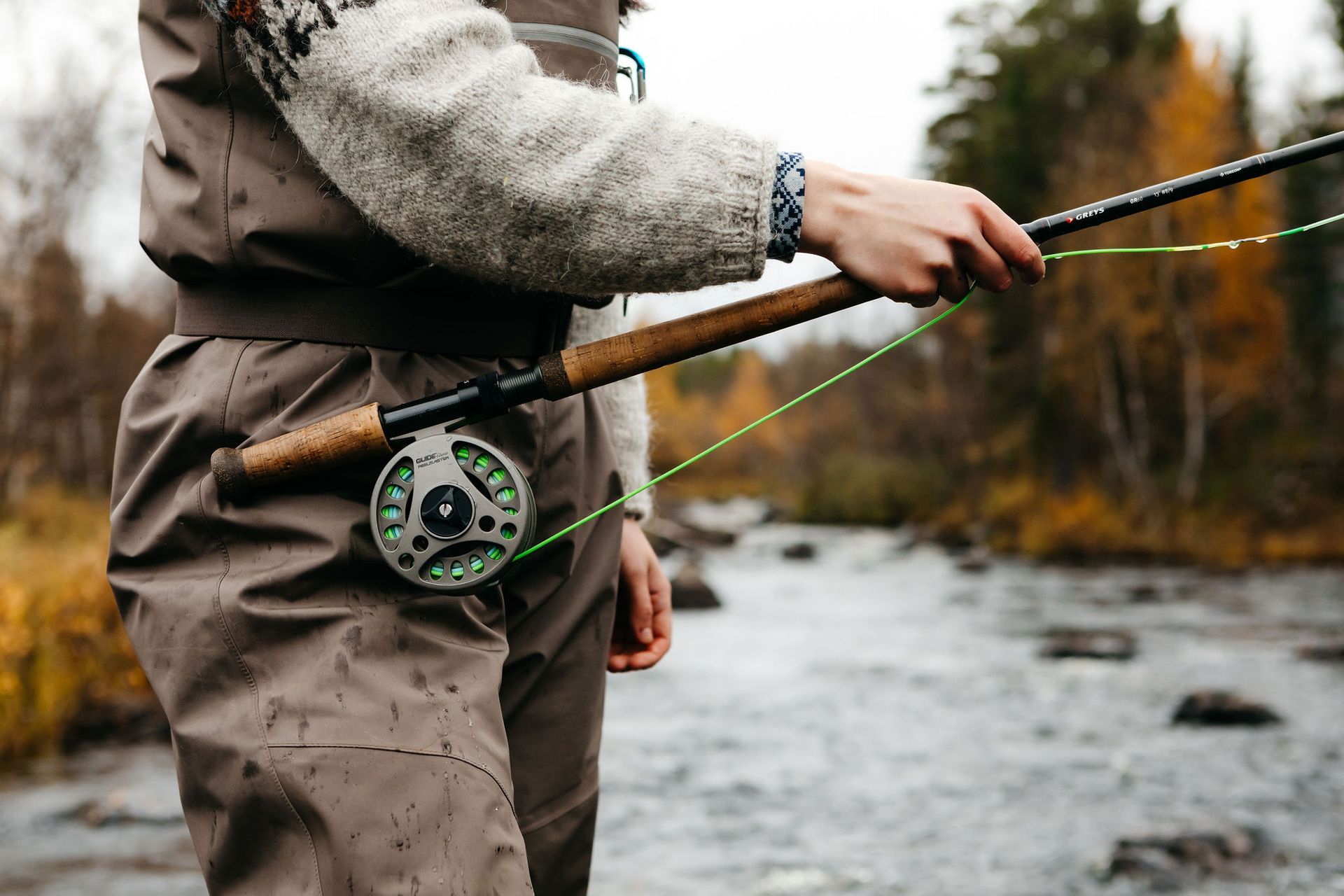 A man is fishing in a river with a fly rod.