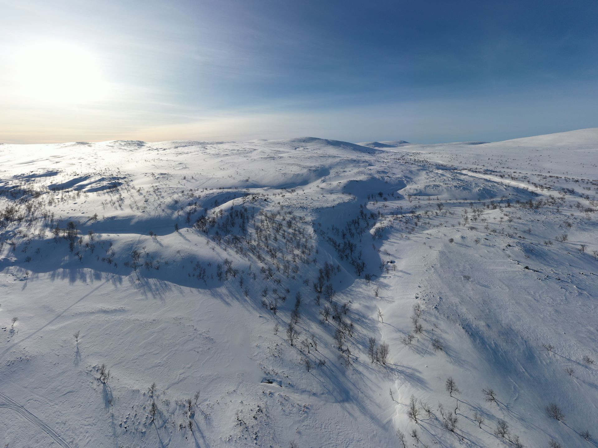 Snow-covered mountains and valleys under a bright sky at sunrise