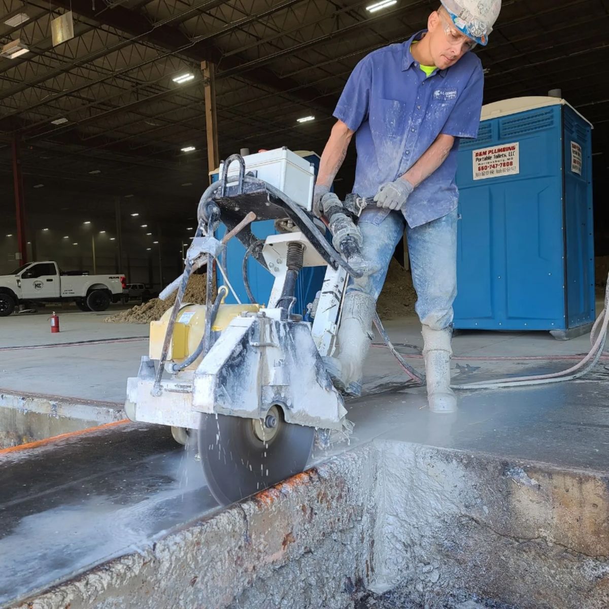 KC Coring & Cutting technician operating a walk-behind slab saw to cut a concrete curb section
