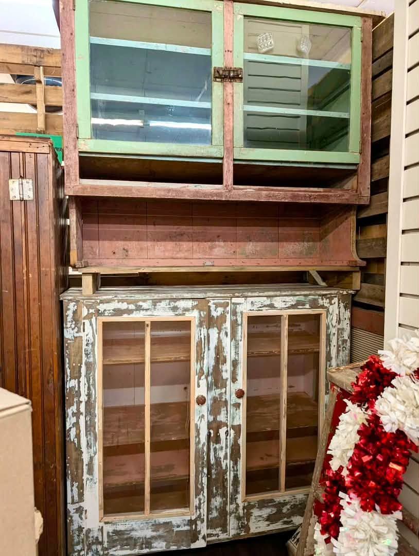 Weathered wooden cabinet with green sliding doors and peeling paint in a workshop or storage space