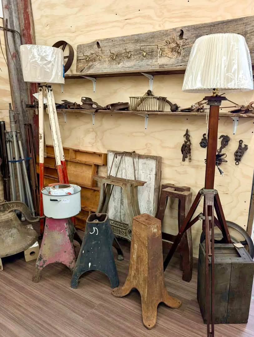 Rustic interior with assorted old wooden stands, lamps, and weathered decor against a peeling wall