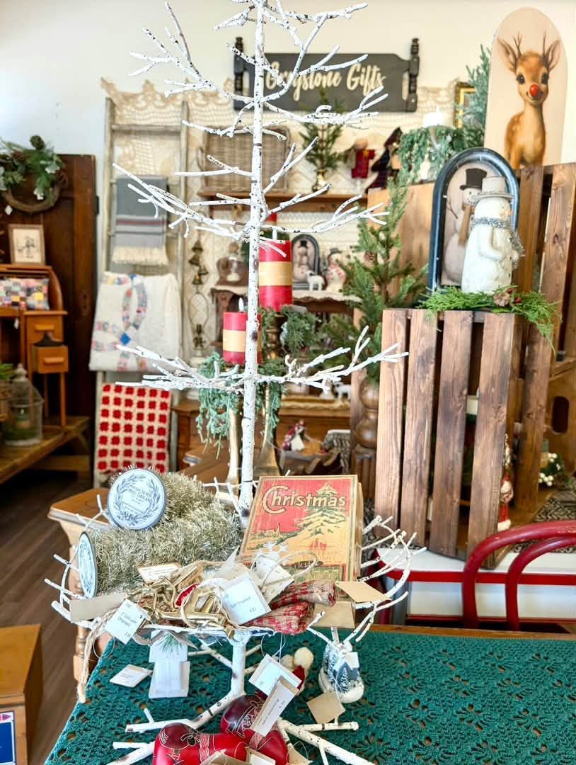 Decorated indoor holiday display with white branches, red accents, and rustic wooden crates