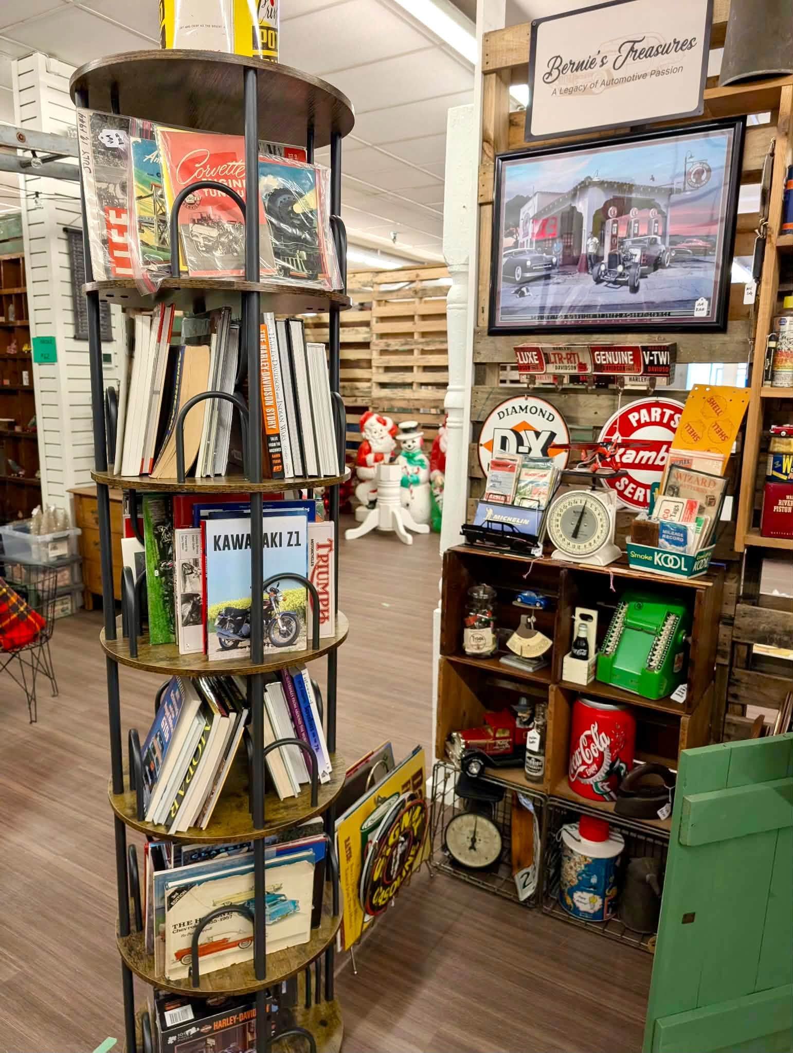 Round metal book display in a shop aisle with books, signs, and souvenirs on surrounding shelves.