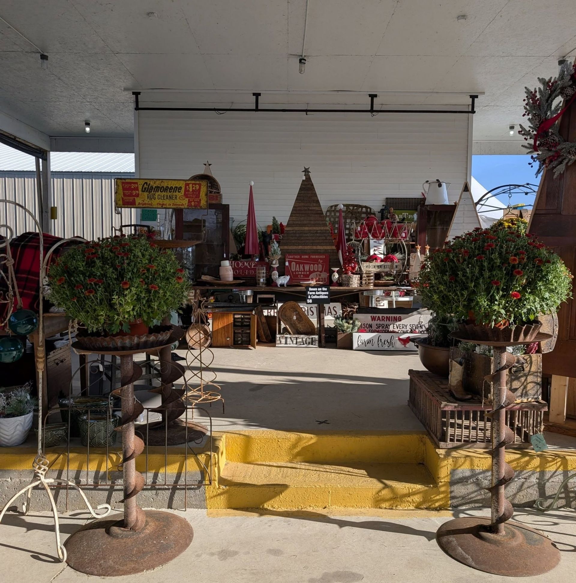 Outdoor shrine altar with flowers, candles, and offerings under a covered pavilion, centered on a yellow step area