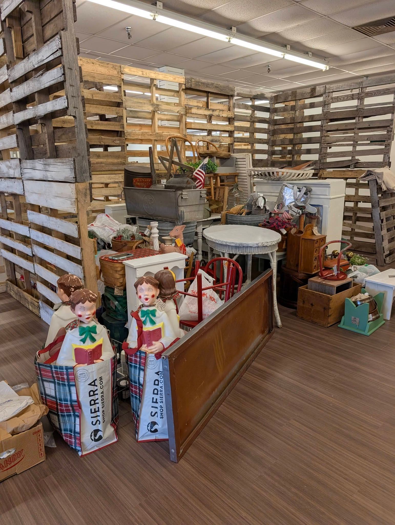Rustic market stall with wooden shelves, produce crates, and decorative dolls in a bright indoor space