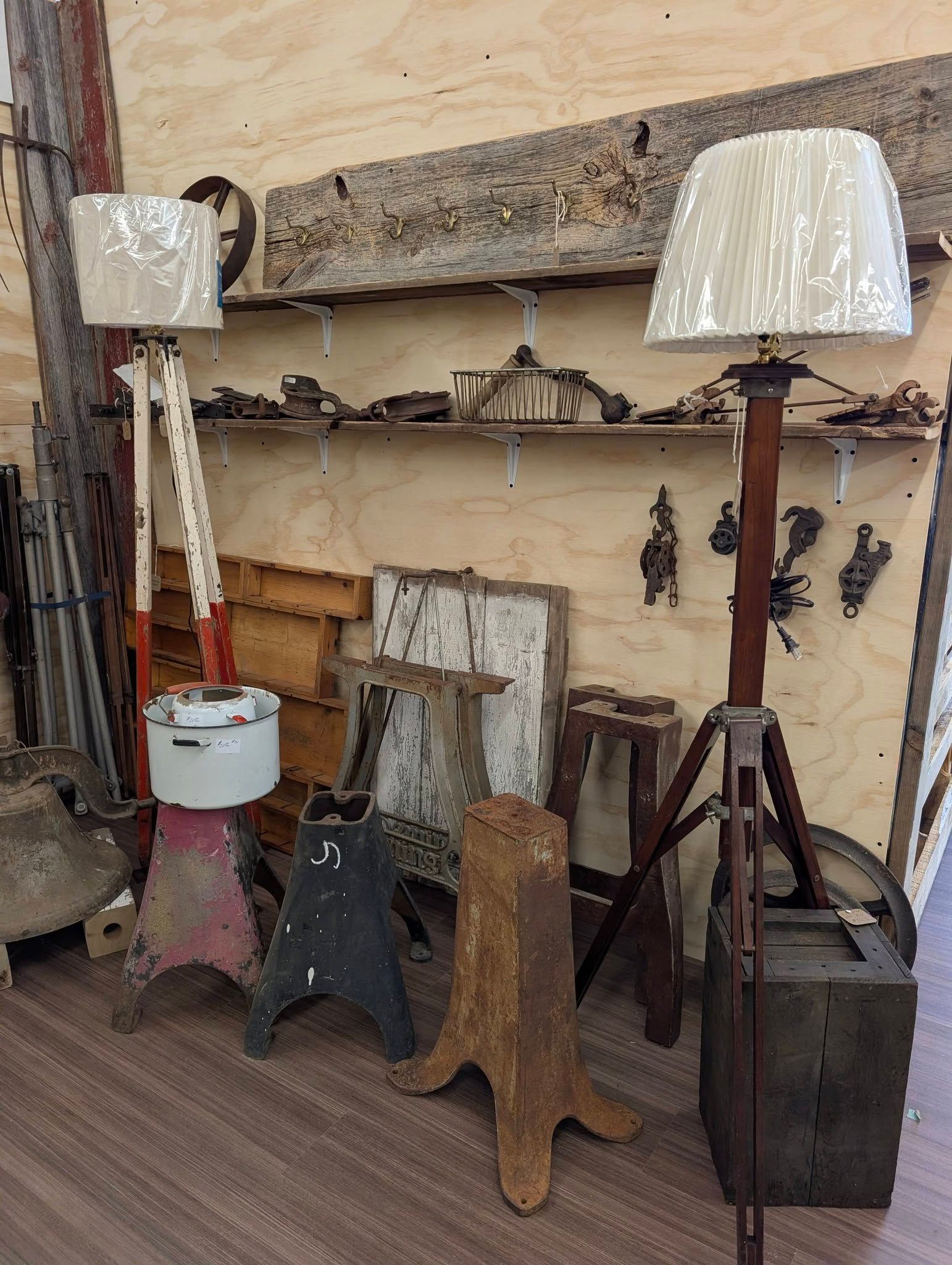 Rustic display of vintage lamps and chairs against a weathered wall in an outdoor market setting