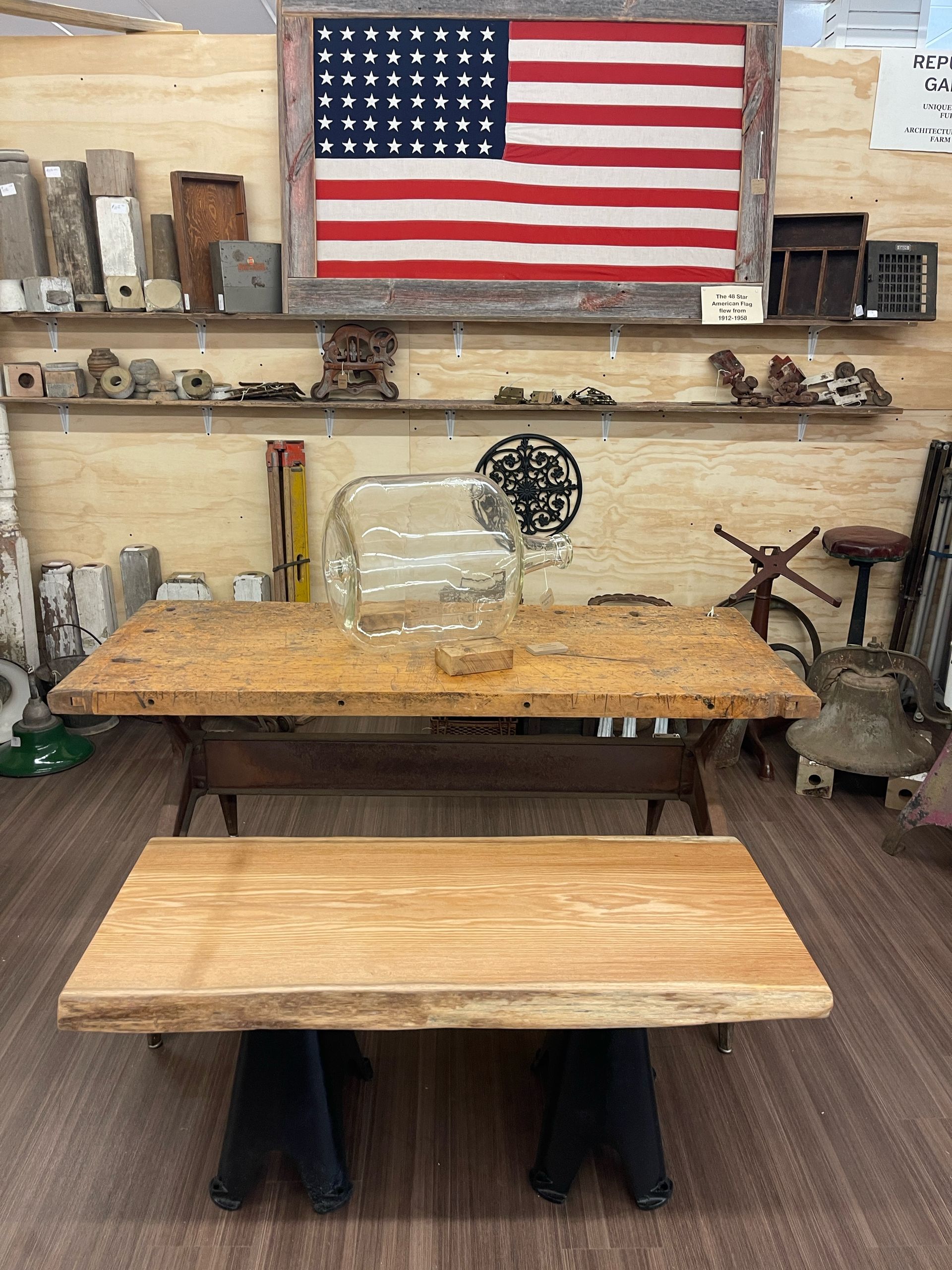 Woodworking shop with American flag, workbench, and wooden table in the foreground