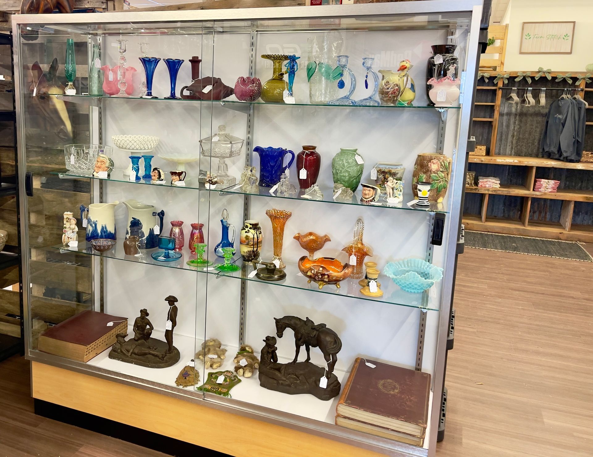 Glass display case of colorful vintage glassware and collectibles in a shop or museum.