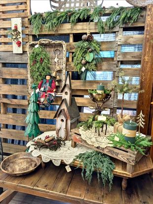 Rustic craft display with woven birdhouses, mossy greenery, and small decorative figures on wooden pallets