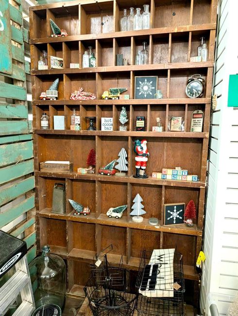Wooden shelf of holiday decorations and small figurines against a white brick wall