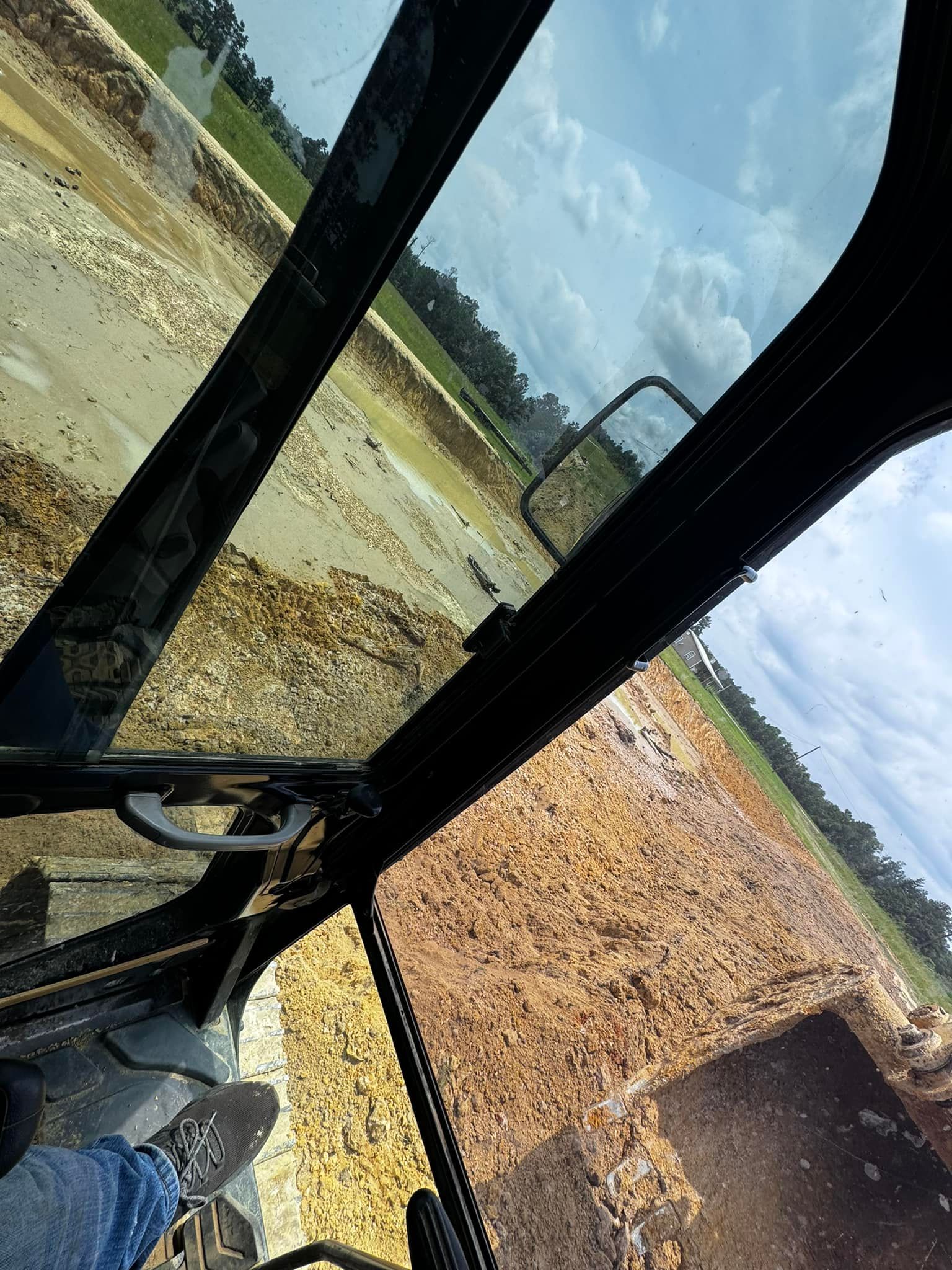 View from inside heavy machinery cab, looking down at wood chips, blue sky.