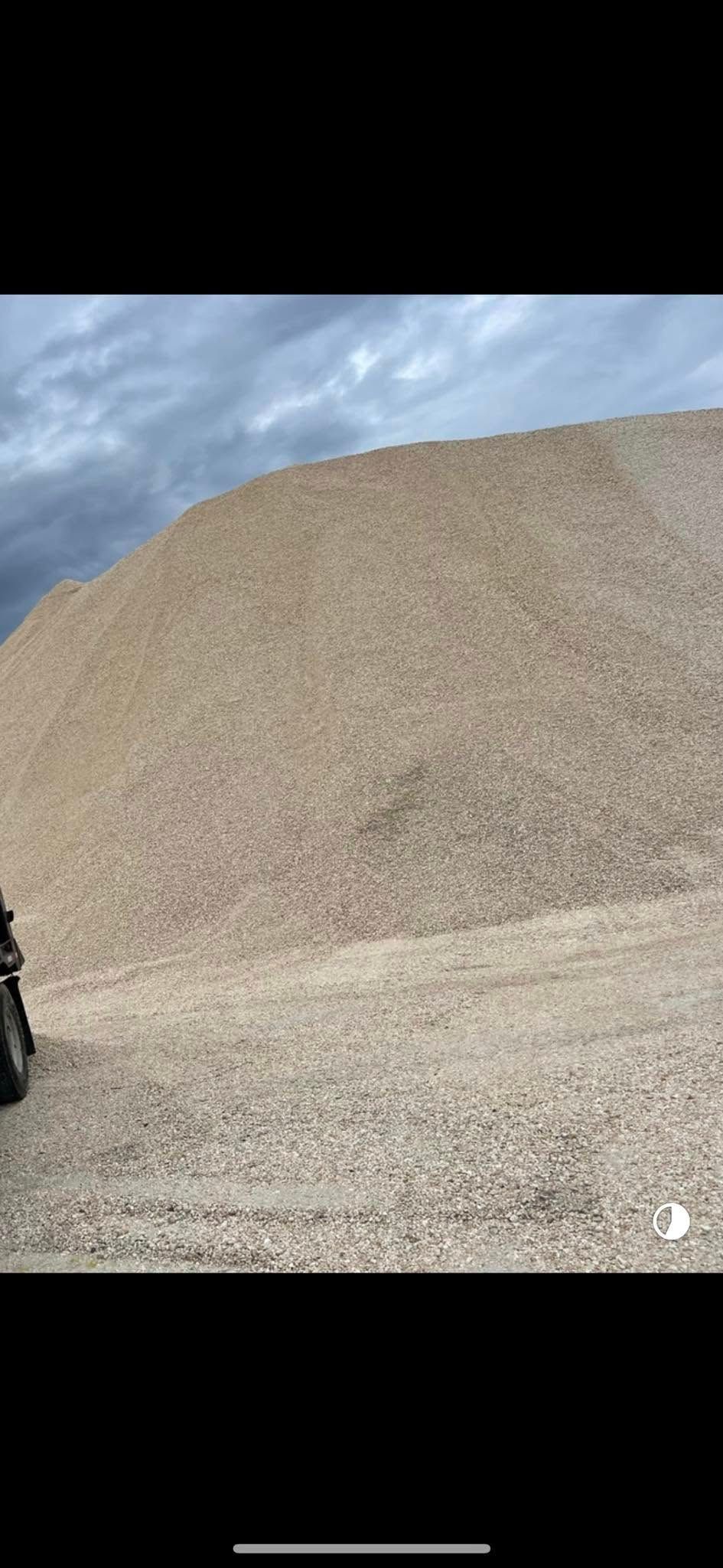 A large pile of gravel under a cloudy sky.