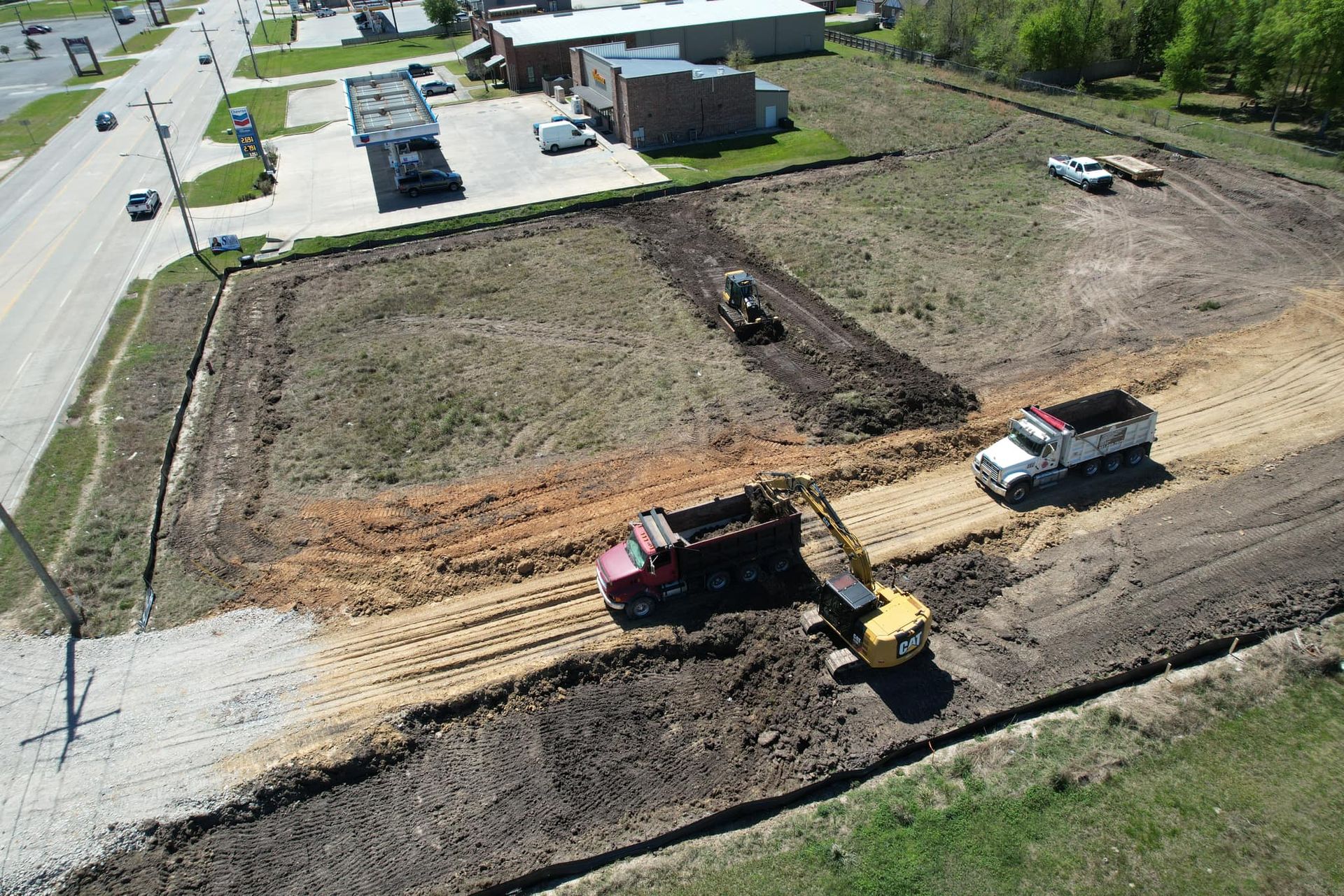Construction site with trucks, an excavator, and a tractor grading land.