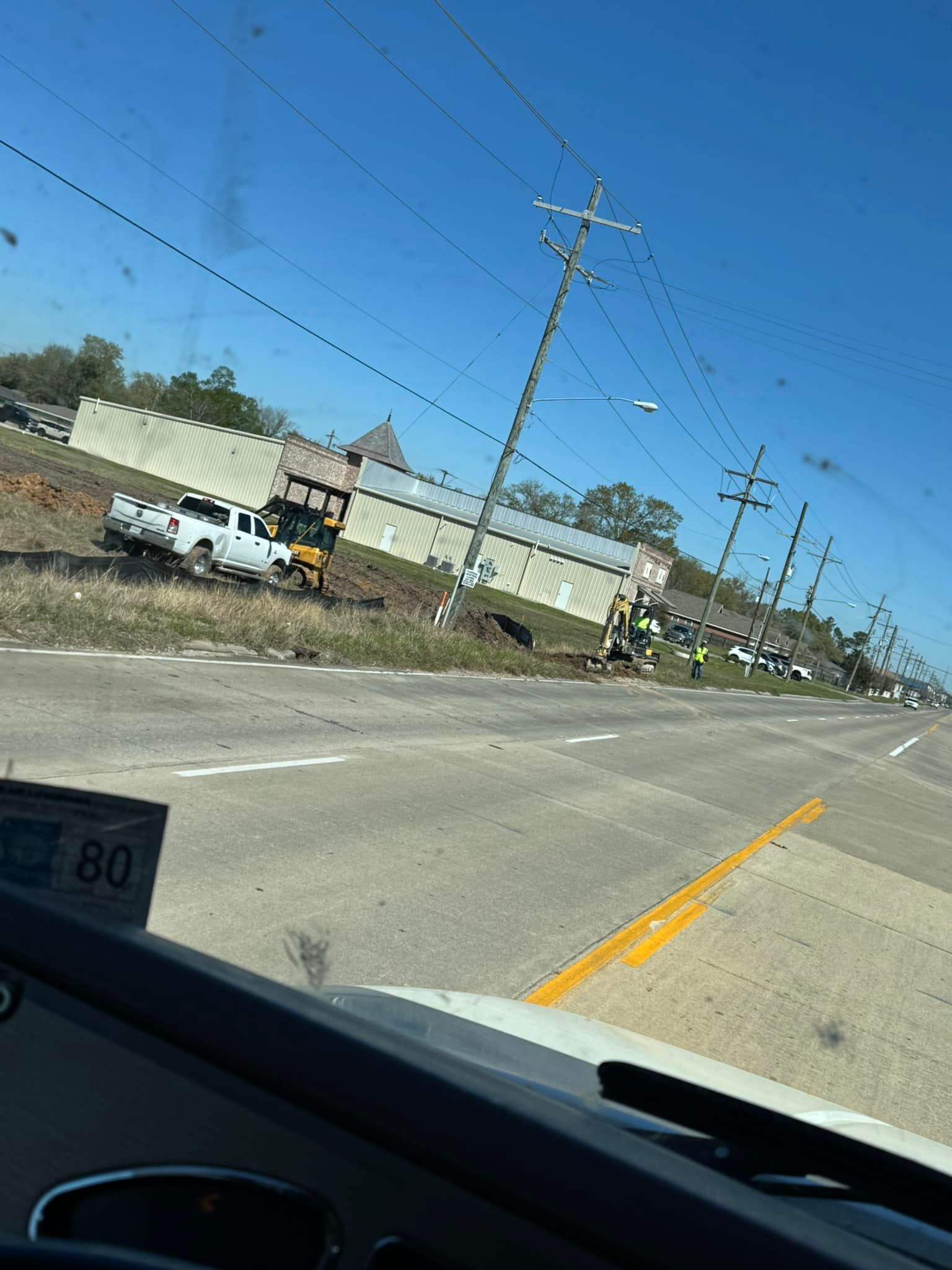 White truck crashed near power lines, workers on site; building in the background, sunny day.