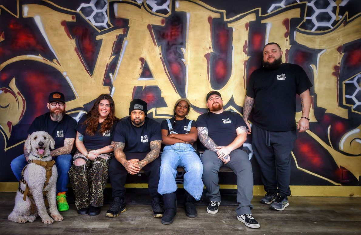 Group of people and a dog posing in front of graffiti-style 