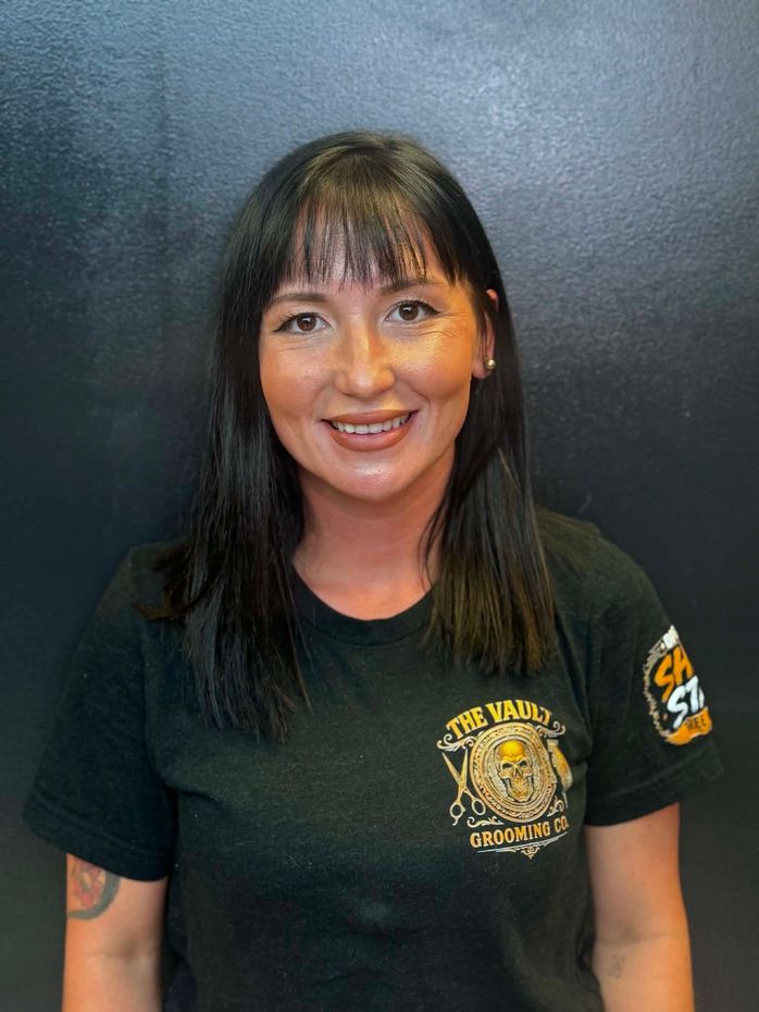 Woman in leopard pants and black shirt, seated and smiling in a black chair against a dark backdrop.