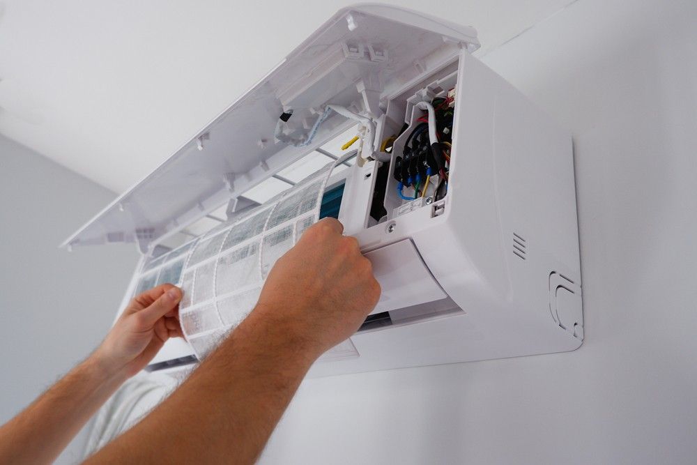 A Person is Cleaning the Filter of an Air Conditioner — A J Wilcox Air & Electrical in Banora Point, NSW
