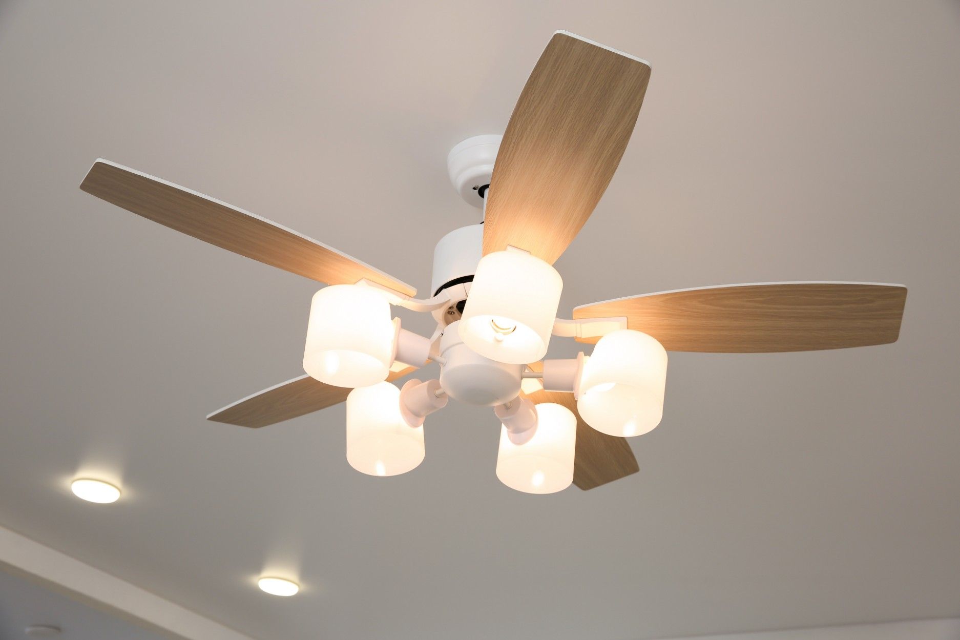 A Ceiling Fan With Wooden Blades is Hanging — A J Wilcox Air & Electrical in Banora Point, NSW