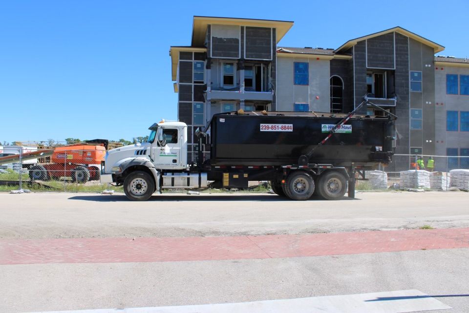 White dump truck parked in front of an apartment building on a sunny day
