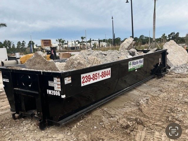 Black construction dumpster on a dirt lot, with company decals and phone number visible.