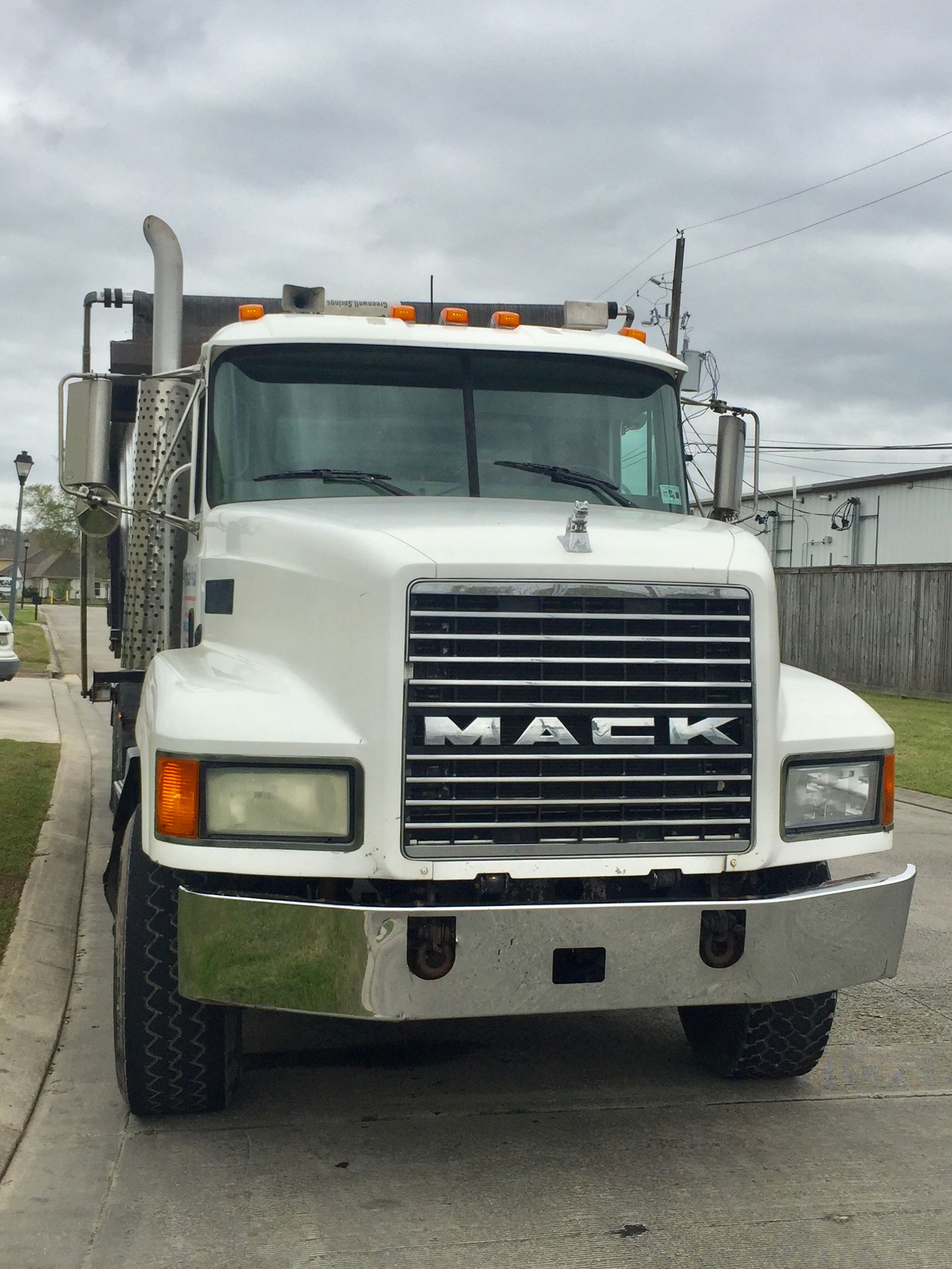 White Mack semi truck parked on a street under cloudy skies