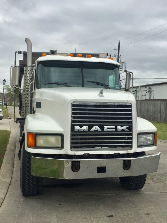 White Mack semi truck parked on a street under a cloudy sky