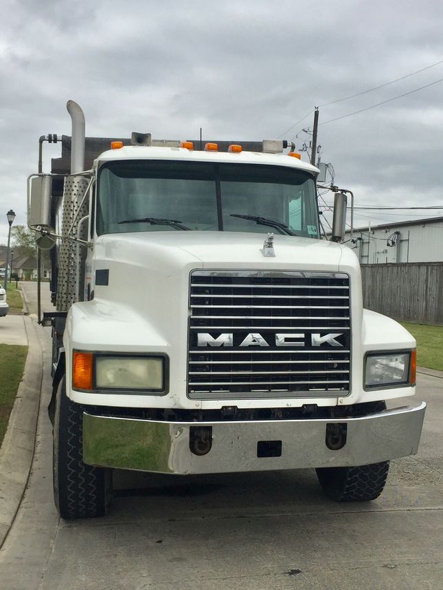 White Mack semi truck parked on a street under a cloudy sky