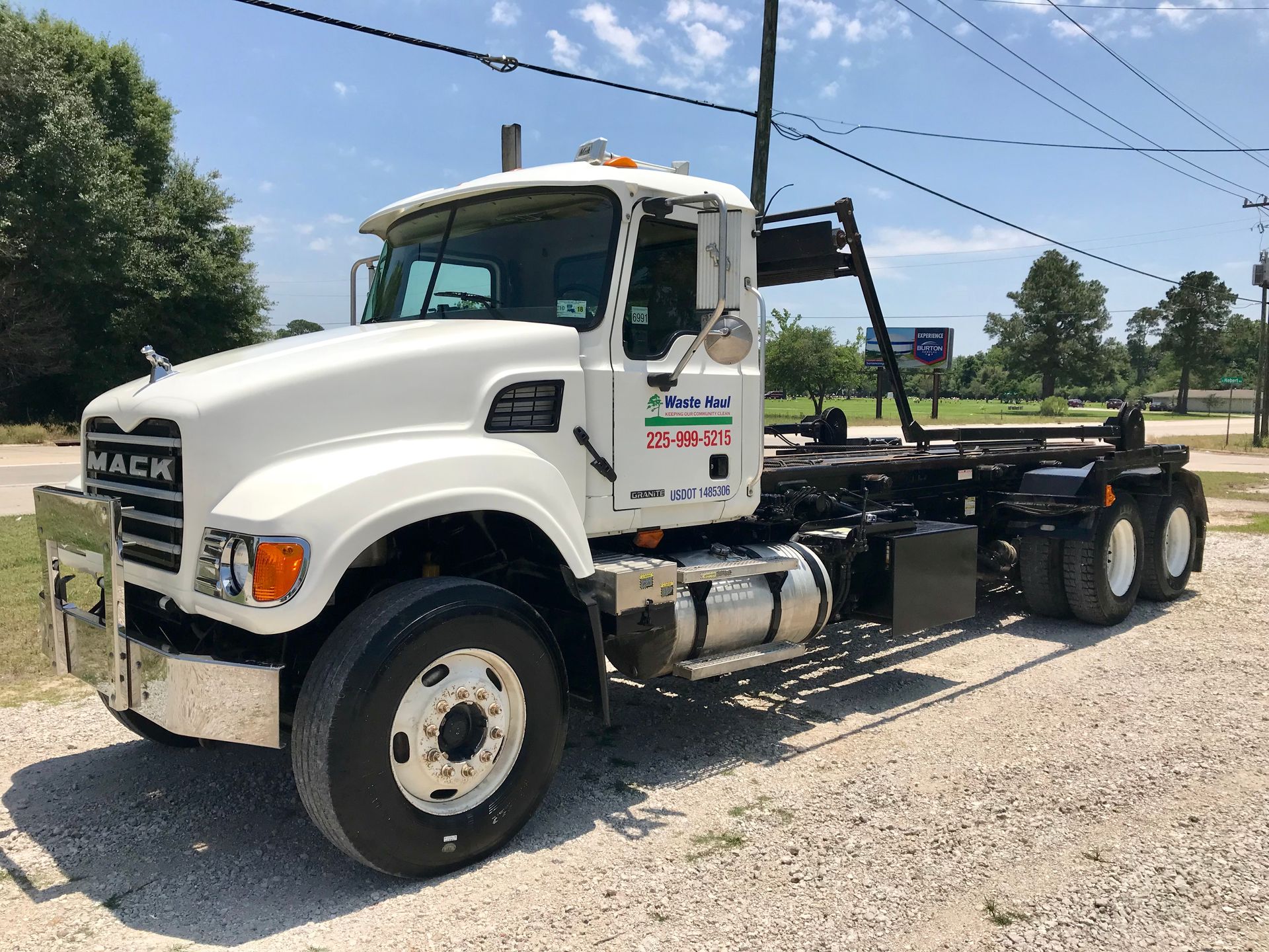 White Mack semi-truck chassis parked on a gravel lot under a blue sky.