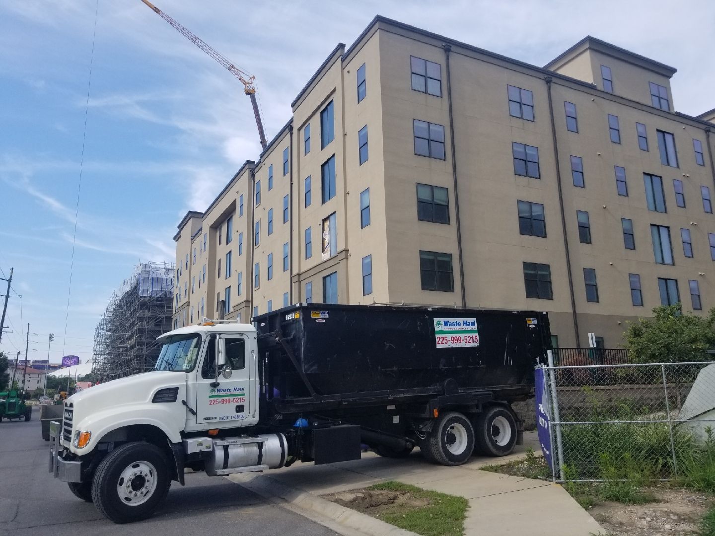White dump truck parked beside a beige apartment building under a blue sky