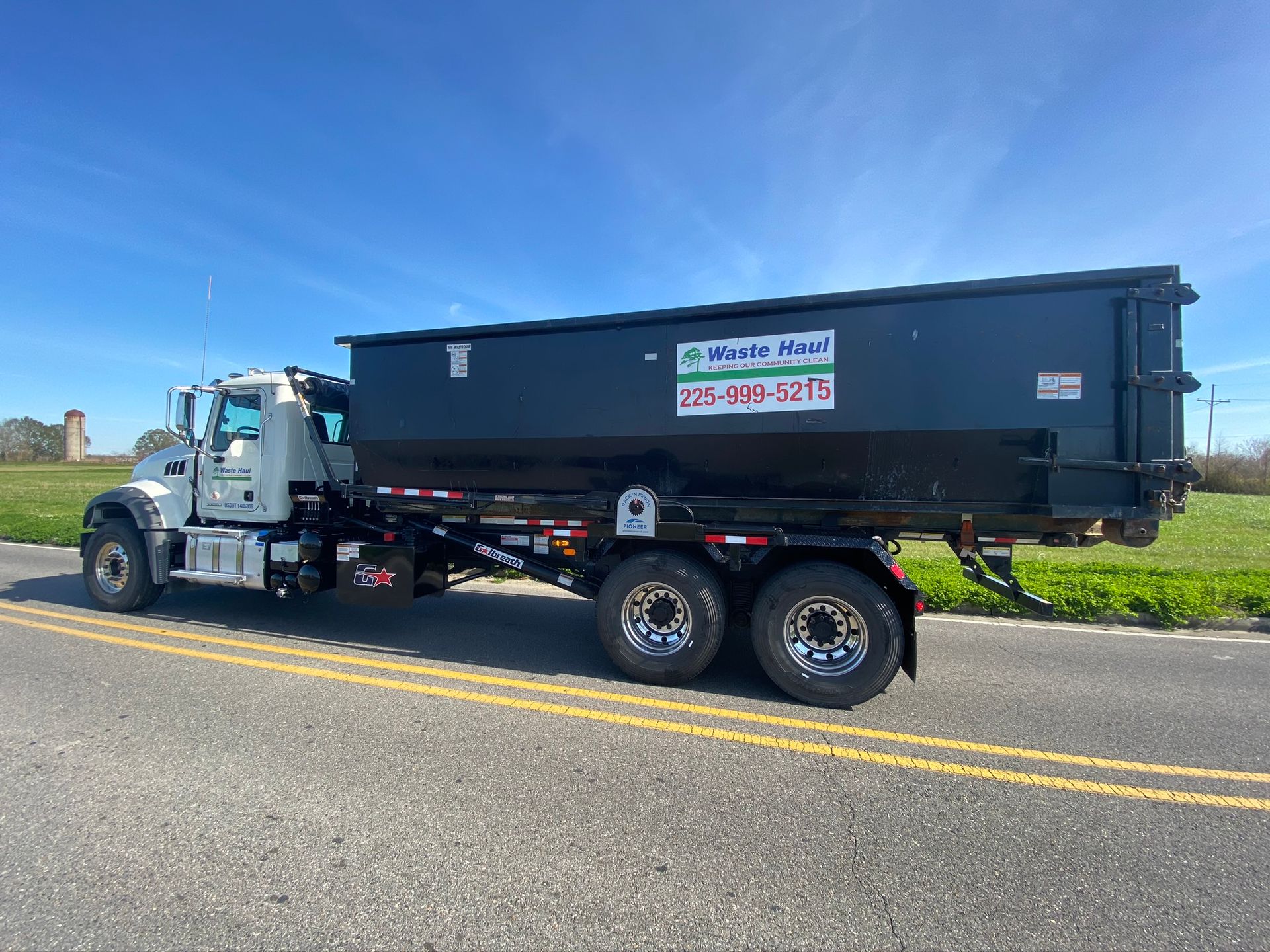 Black dump truck parked on a road under a clear blue sky